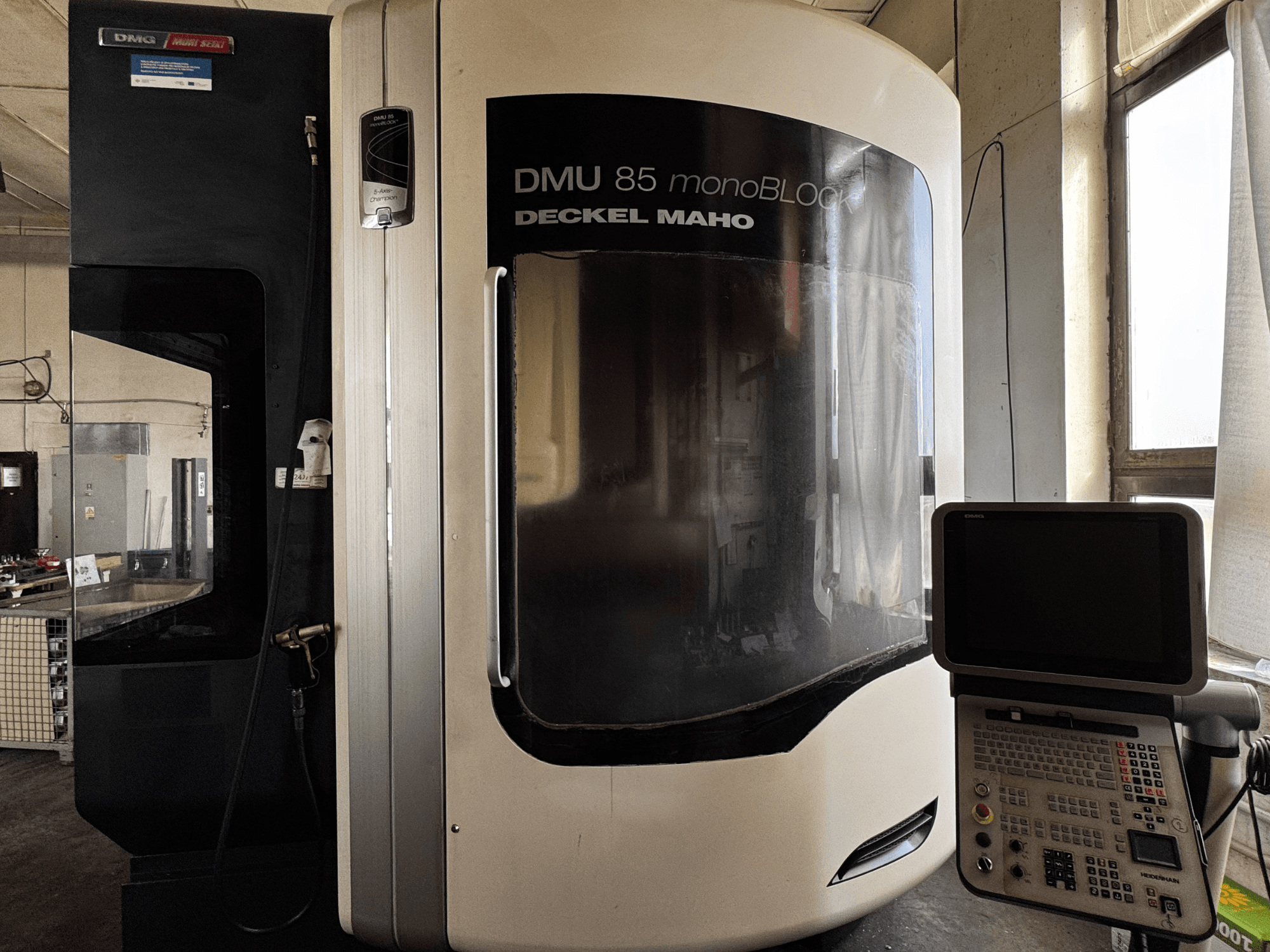 DMG MORI DMU 85 monoBLOCK verticaal bewerkingscentrum, vooraanzicht met bedieningspaneel en groot kijkvenster.