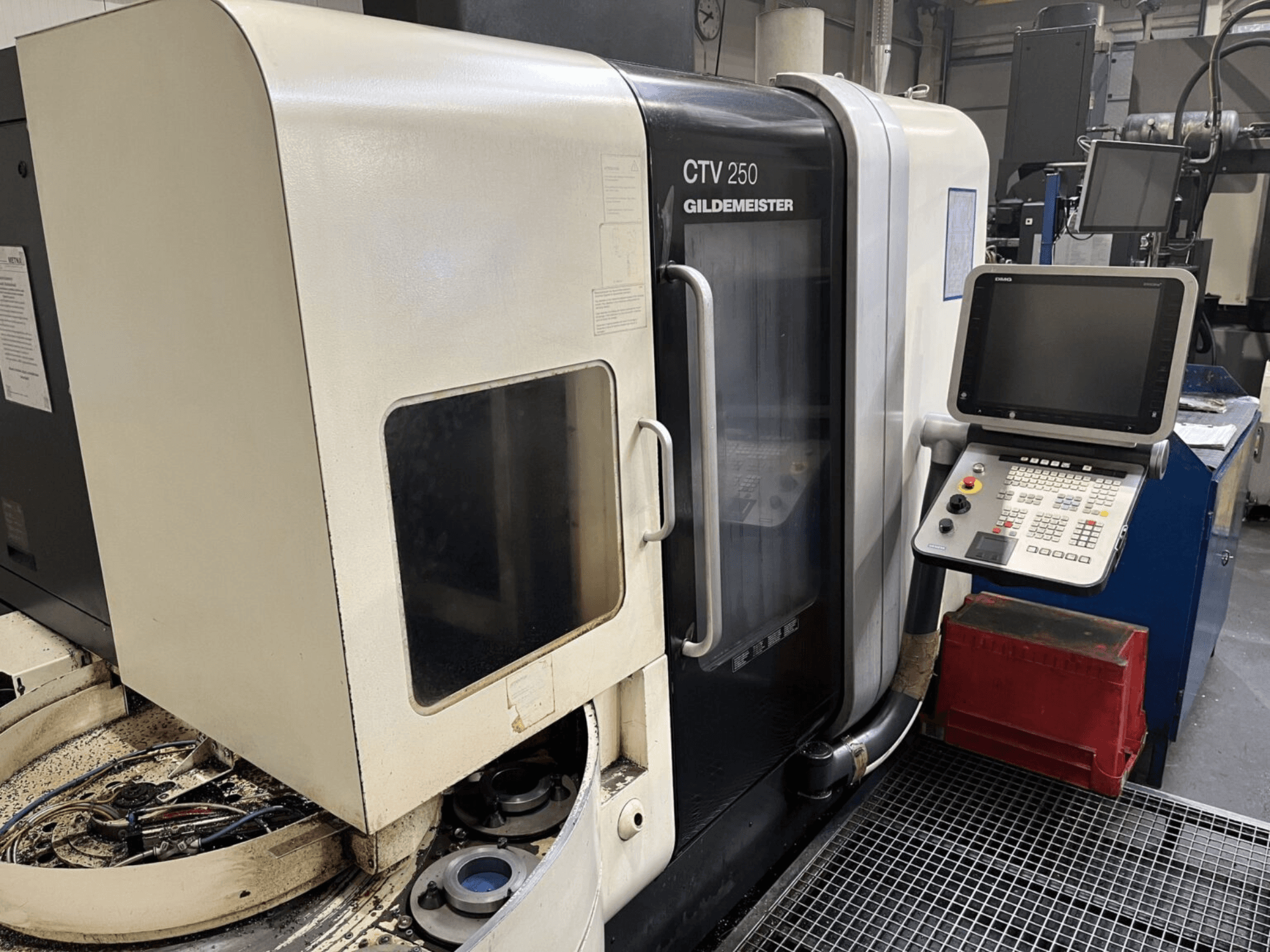 Verticale draaimachine DMG CTV-250 gezien vanaf de voorkant, met het bedieningspaneel en het werkgebied met gereedschappen.