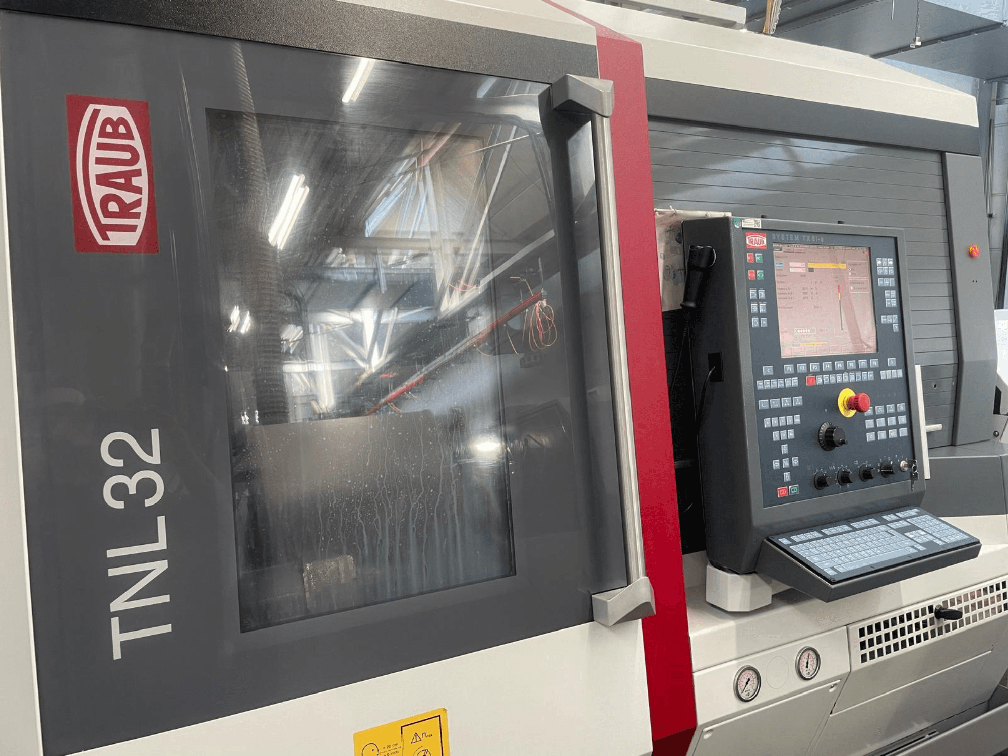 Traub TNL32 CNC draaibank vooraanzicht, met bedieningspaneel met knoppen, beeldscherm en slanke metalen behuizing.