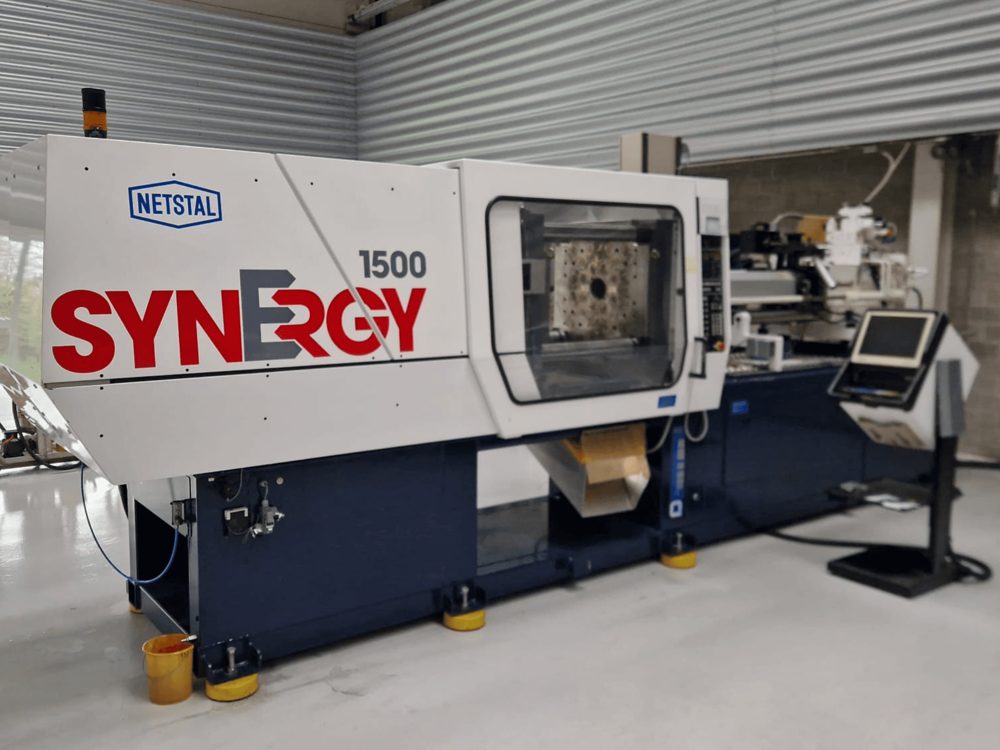 Netstal Synergy 1500-460 hydraulische spuitgietmachine, vooraanzicht, met het bedieningspaneel en het open injectiegedeelte.