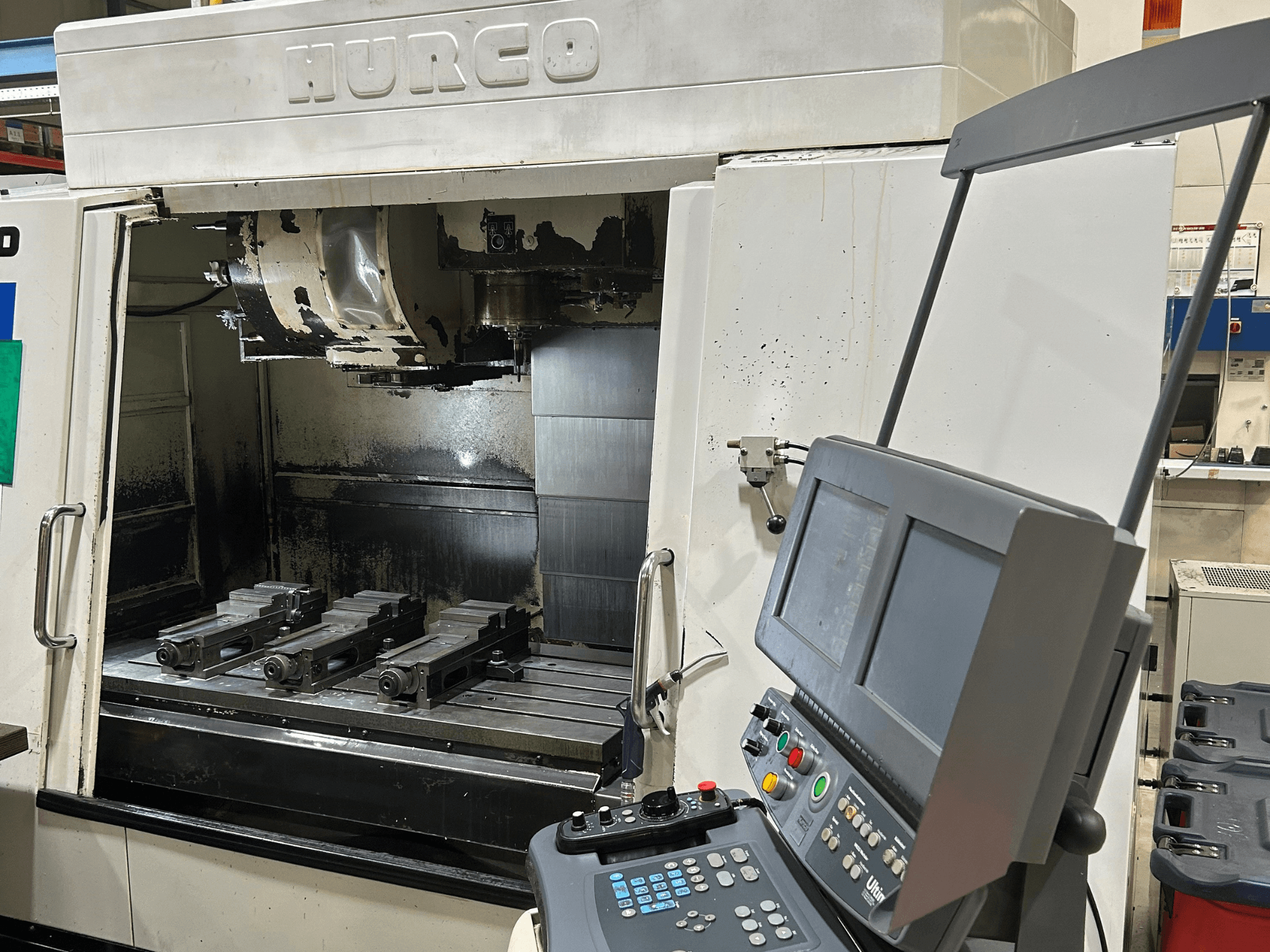 Hurco CNC freesmachine, vooraanzicht, met vier gereedschapshouders op de tafel en een bedieningspaneel met dubbele schermen en knoppen.