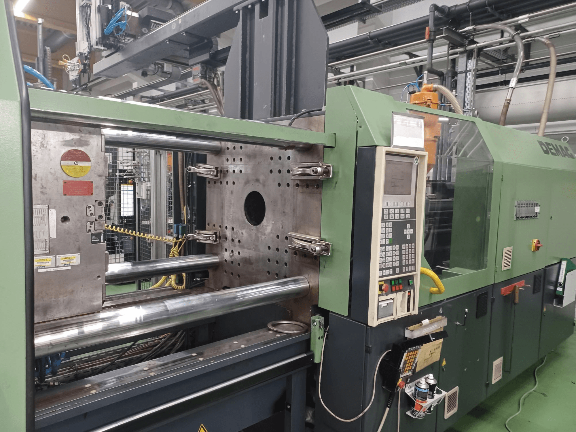 Demag spuitgietmachine, vooraanzicht, met bedieningspaneel, metalen hydraulische cilinders en veiligheidsvoorzieningen.