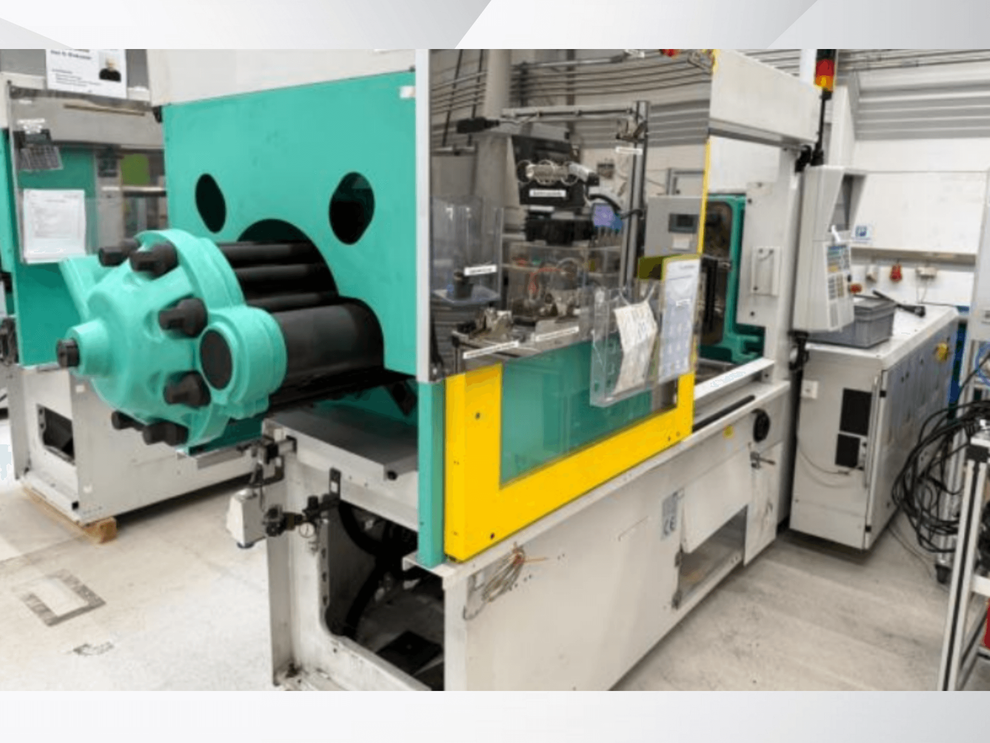 Spuitgietmachine, lichtblauw en geel, vooraanzicht, met zichtbare matrijs en bedieningspaneel met labels.