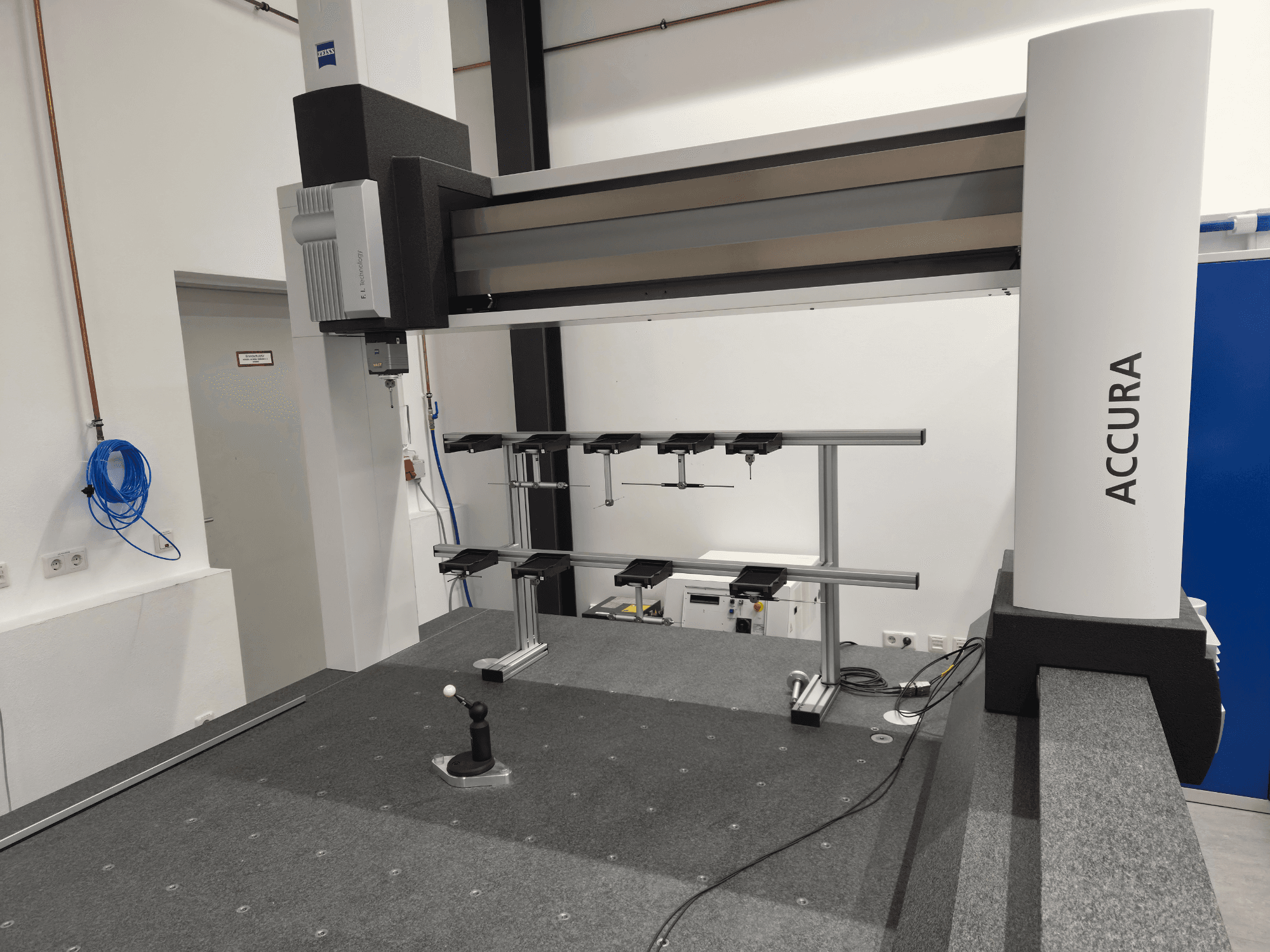 ZEISS ACCURA 16/24/10 CMM in vooraanzicht, met de meetarm, het onderstel en de bedieningsinterface op een grijze, met tapijt beklede ondergrond.