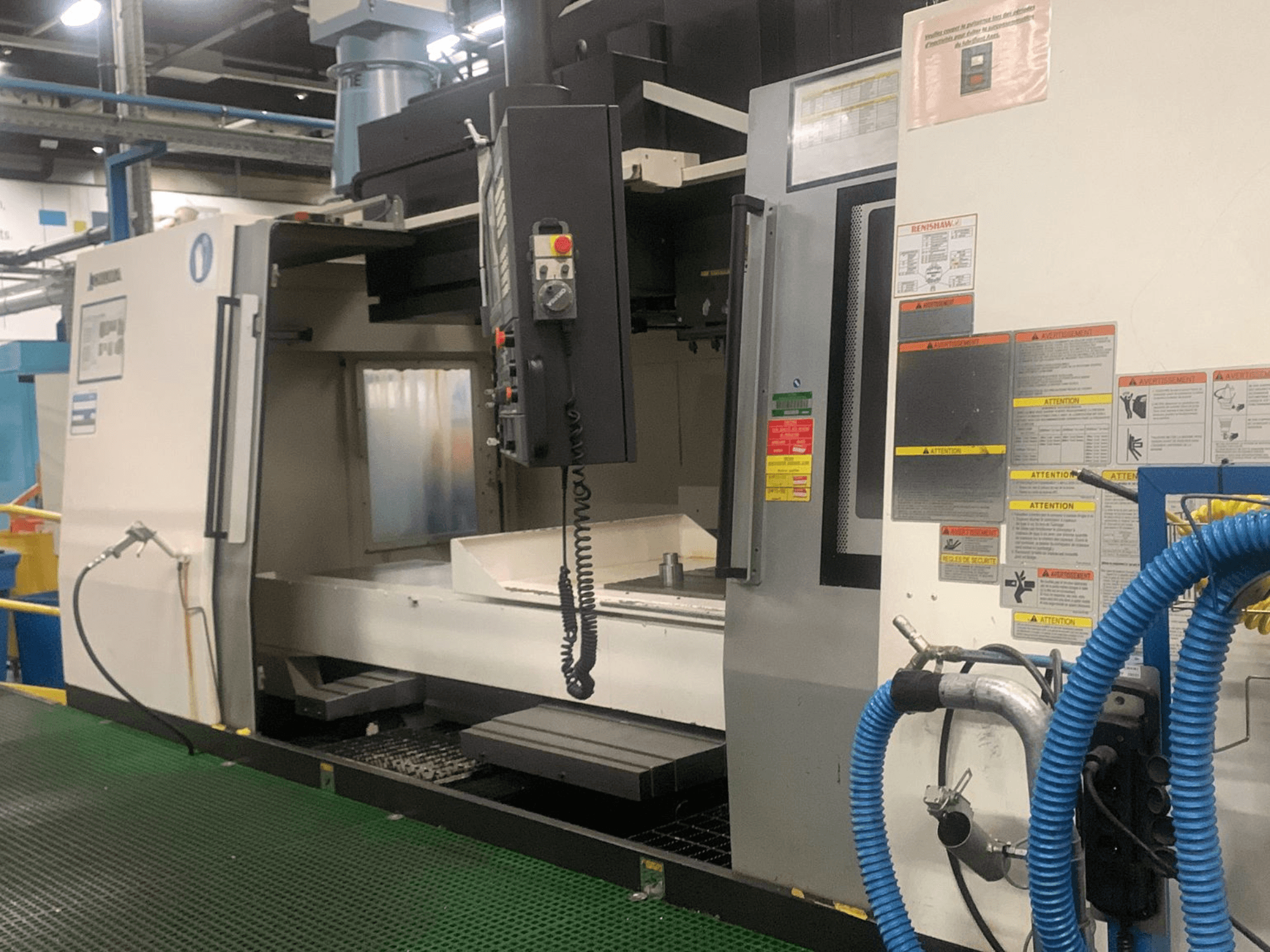 Okuma Millac 852 VII verticaal bewerkingscentrum, vooraanzicht, met weergave van het bedieningspaneel, het spindelgedeelte en de veiligheidslabels.