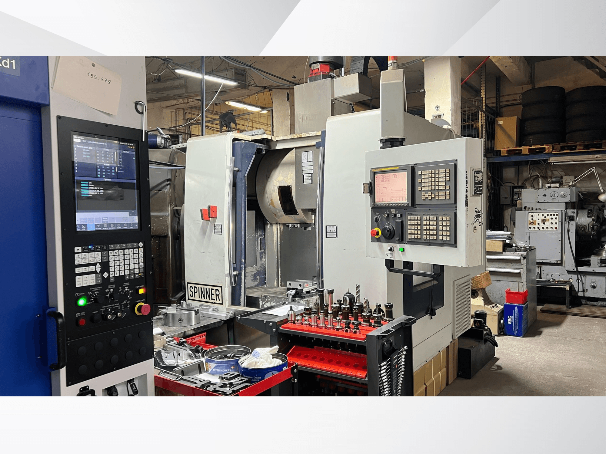 CNC machine met een bedieningspaneel, gereedschappen en werkstukken zichtbaar, gezien vanuit een vooraanzicht in een werkplaatsomgeving.