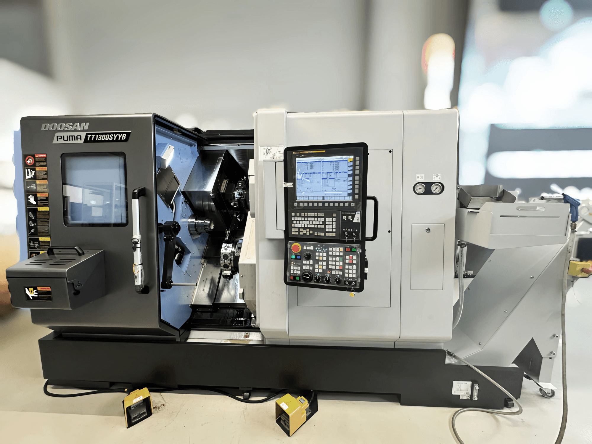 Doosan Puma TT1300SYYB draaifreescentrum in zijaanzicht, met het bedieningspaneel en machine-interieur met zichtbaar gereedschap.