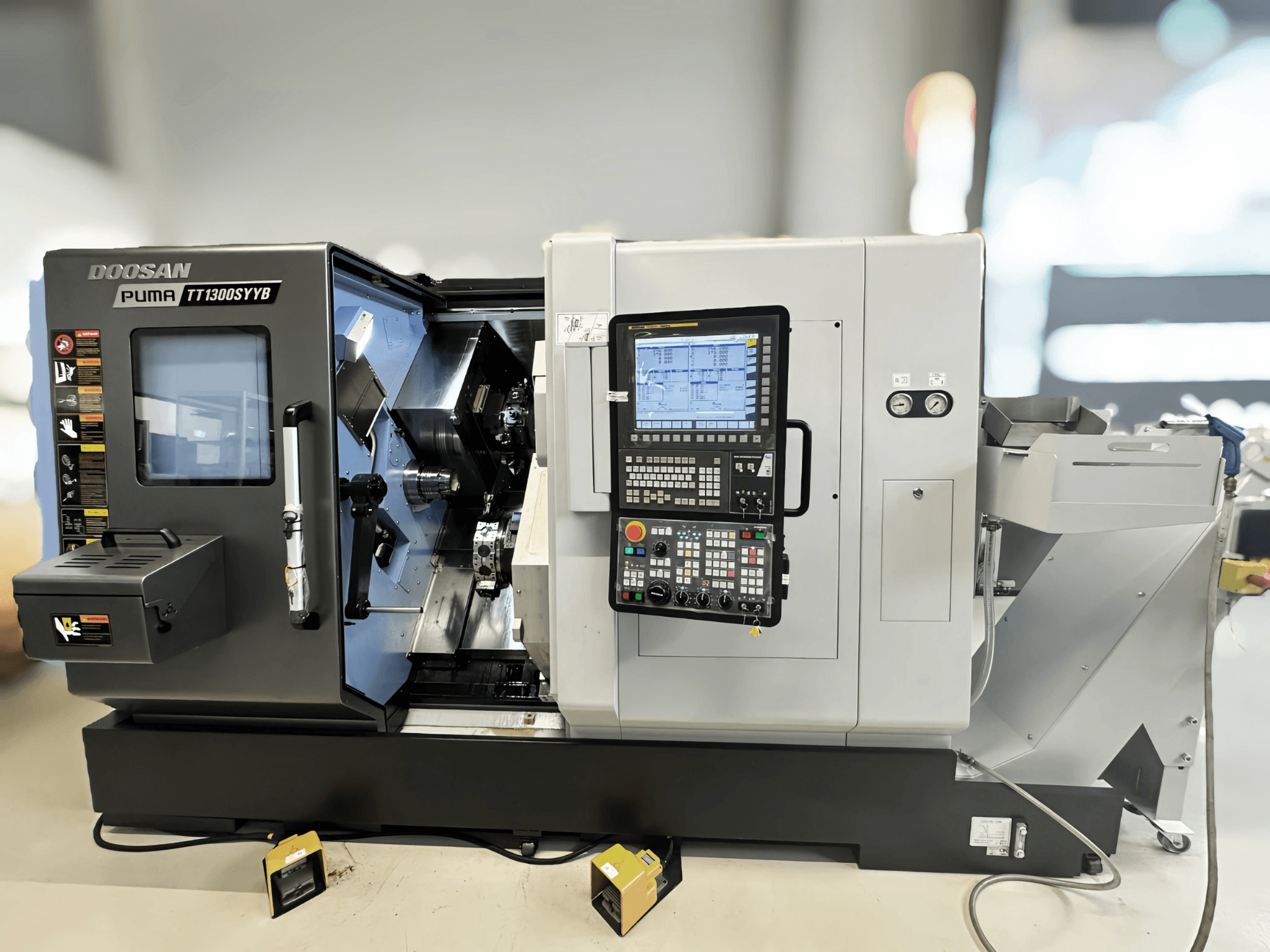 Doosan Puma TT1300SYYB draaifreescentrum in zijaanzicht, met het bedieningspaneel en machine-interieur met zichtbaar gereedschap.