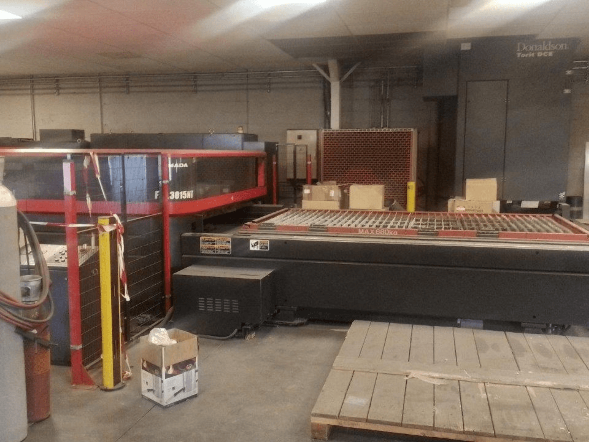AMADA FOL 3015 NT CO₂-lasersnijmachine, vooraanzicht; rode veiligheidsbehuizing, werktafel met rooster, industriële omgeving.