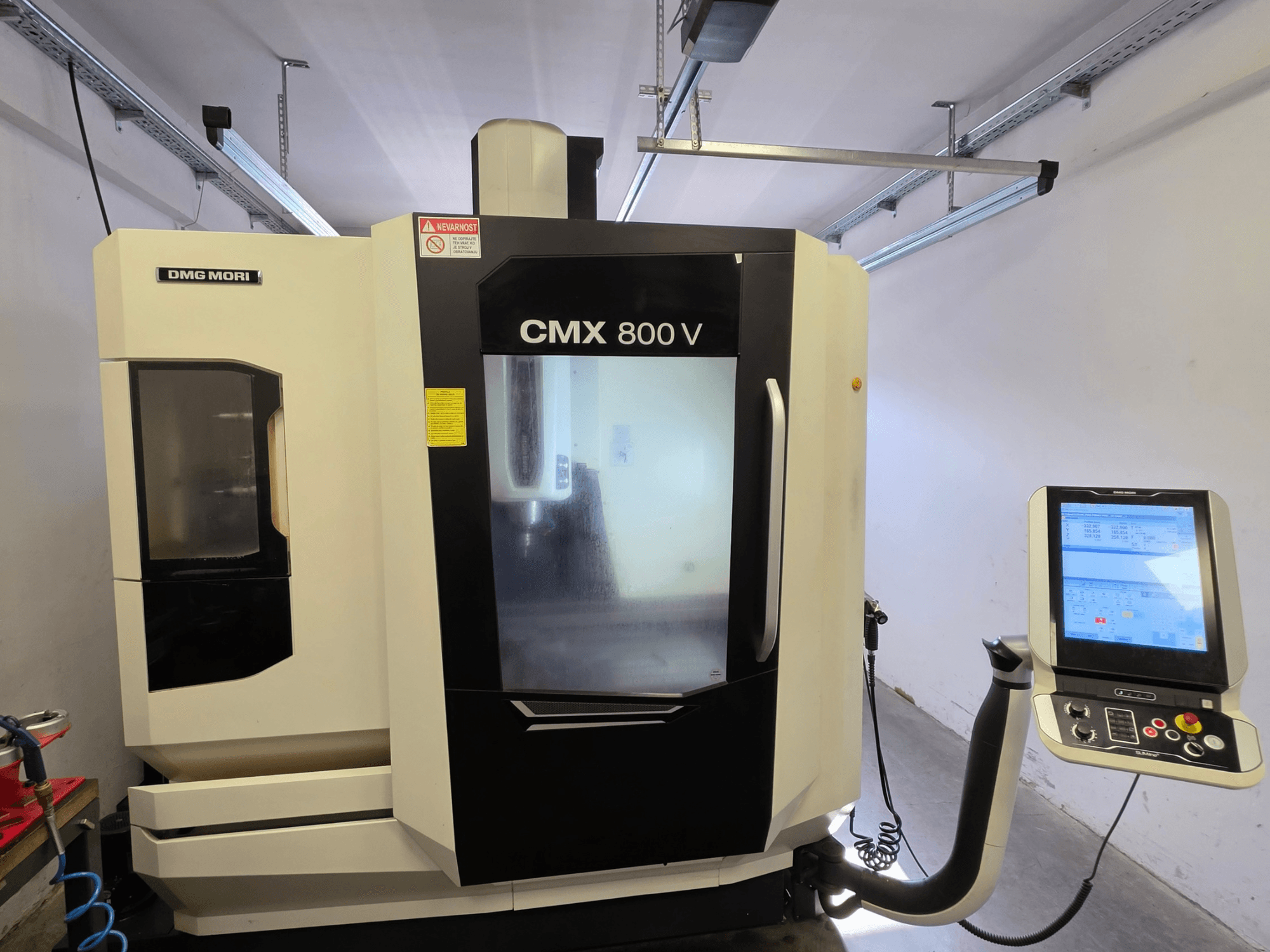DMG MORI CMX 800V verticaal bewerkingscentrum, vooraanzicht, voorzien van een bedieningspaneel met touchscreen en duidelijke veiligheidsmarkeringen.