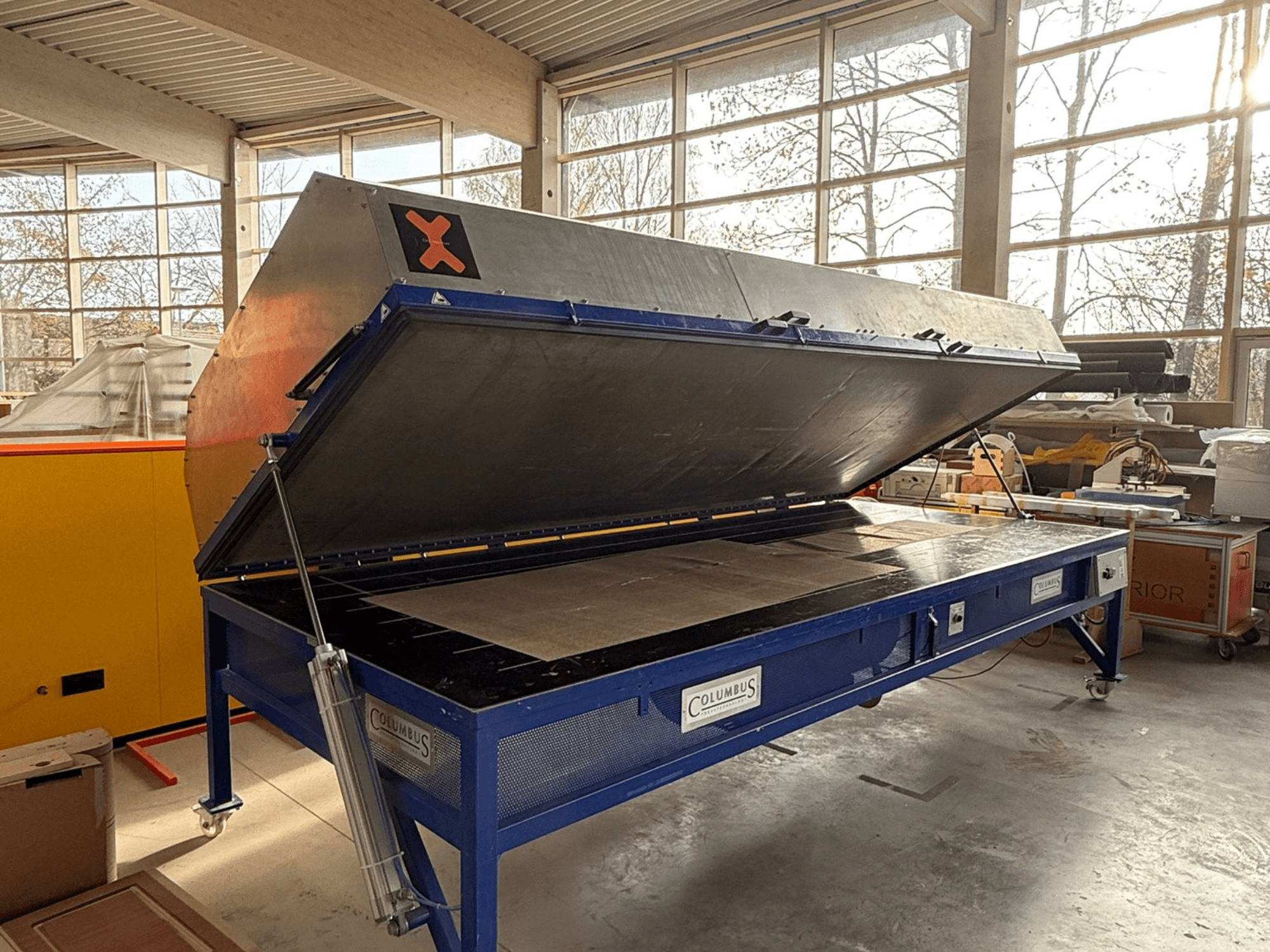 Columbus vacuümpers in een werkplaats, vooraanzicht met grote schuine bovenkant open, die een vlak oppervlak en gedetailleerde machines laat zien.