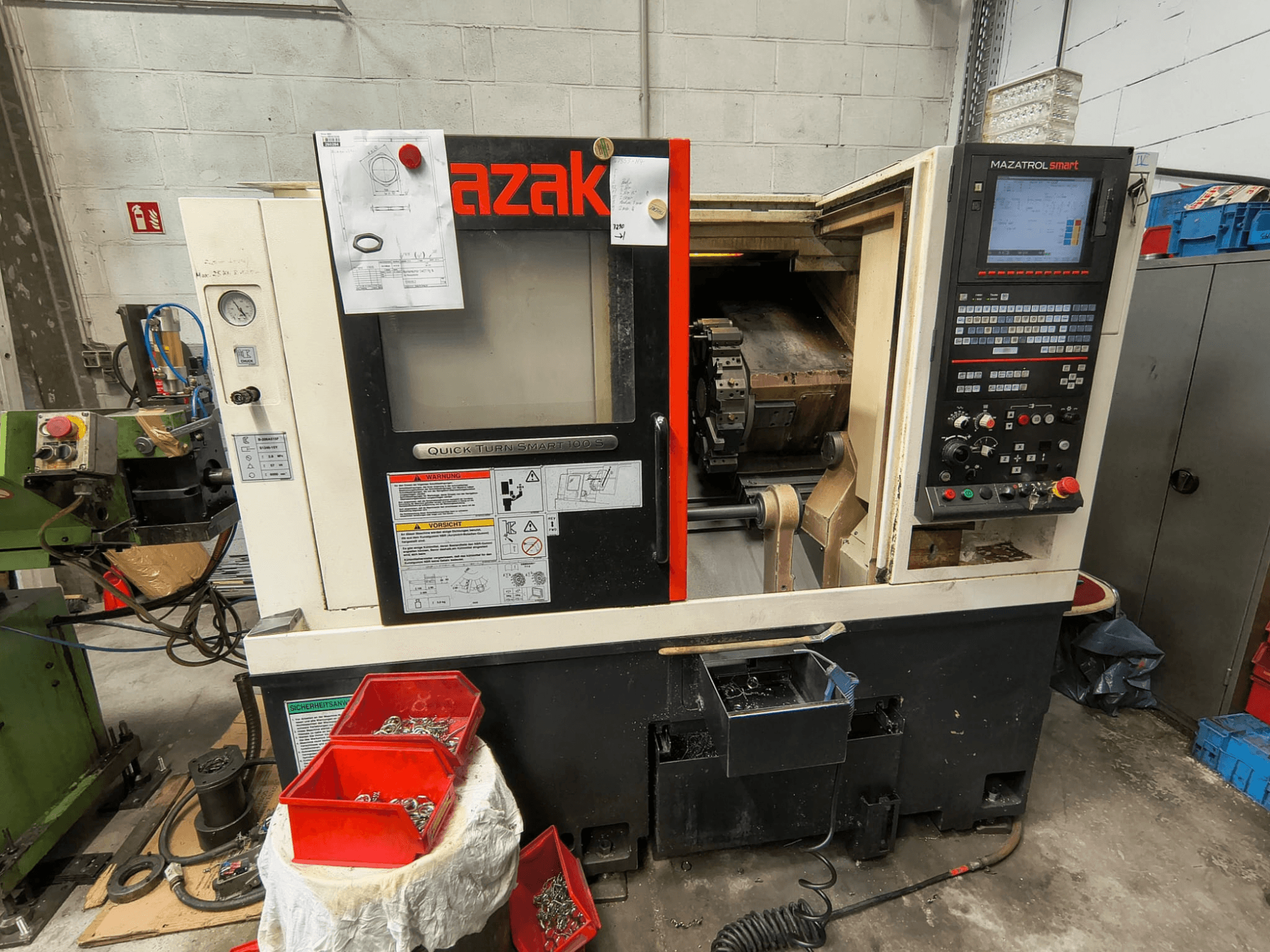 Mazak Quick Turn Smart 100 S, zijaanzicht met bedieningspaneel, koelvloeistofbak en opbergbakken met schroeven.