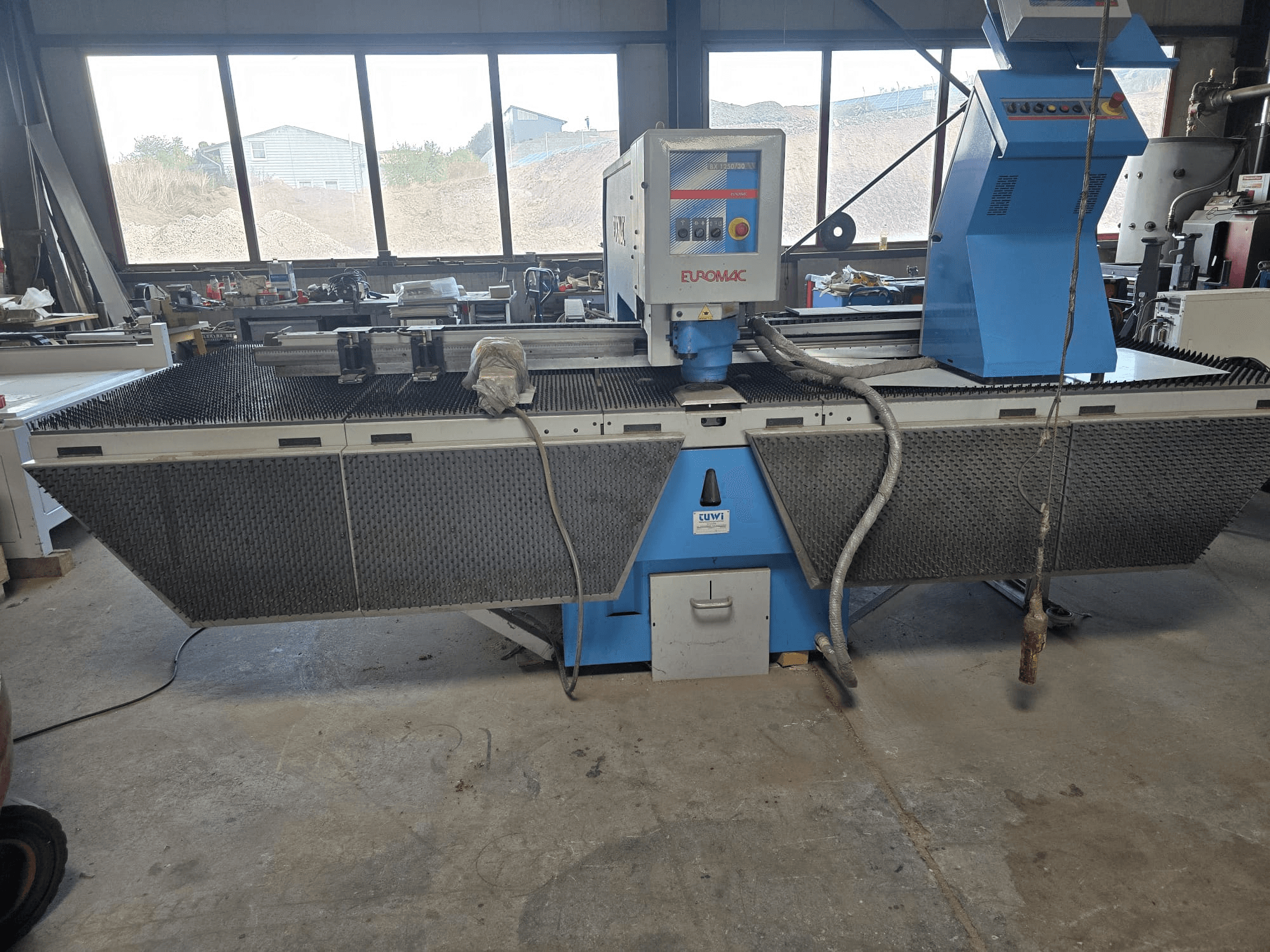 CNC-ponsmachine Euromac BX 1250/30 in een werkplaats, zijaanzicht met de bedieningselementen, het industriële ontwerp en het metalen snijbed.