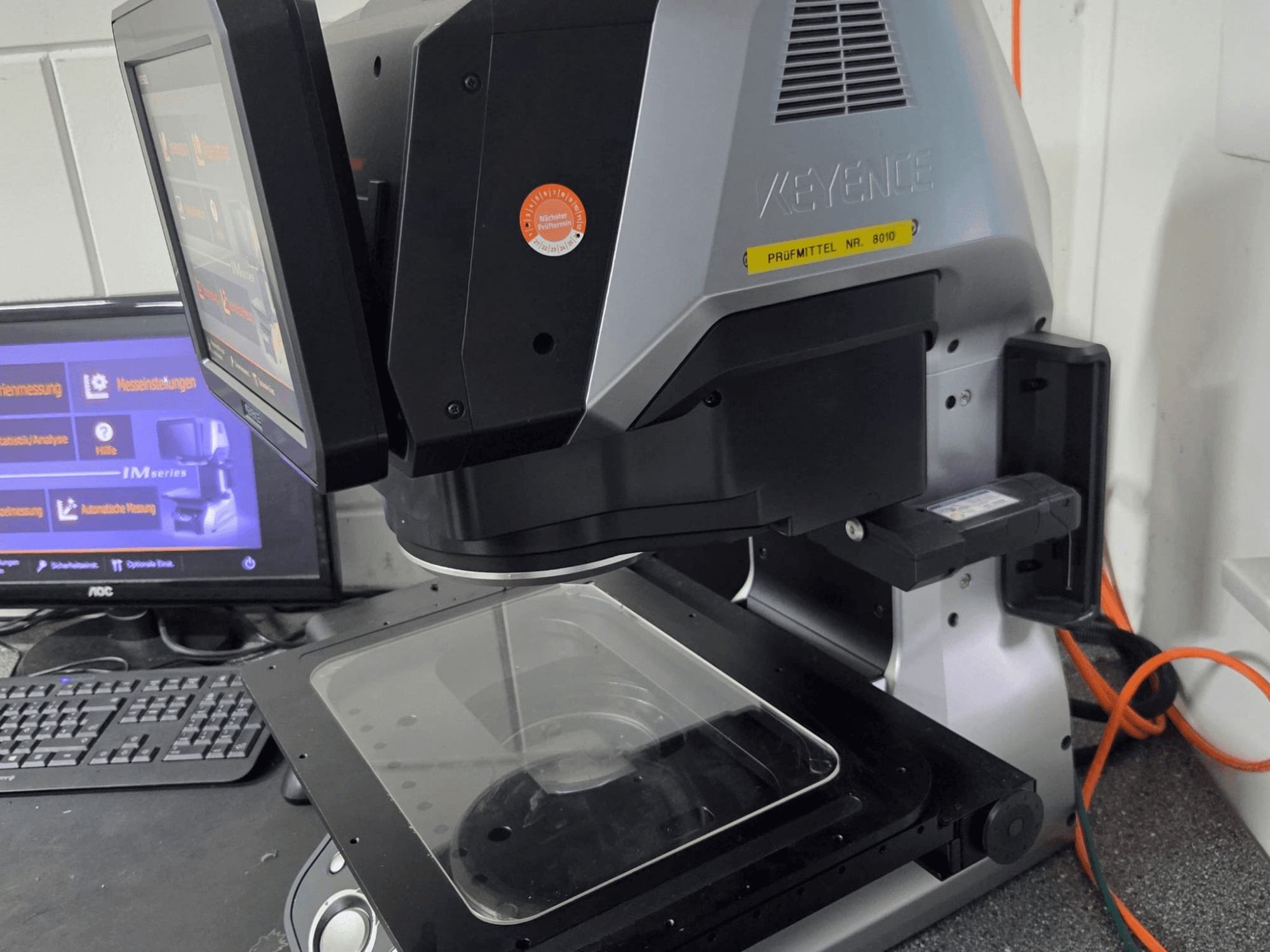 KEYENCE IM 7030 optische meetmachine, vooraanzicht met touchscreen display en glazen meetplaat.