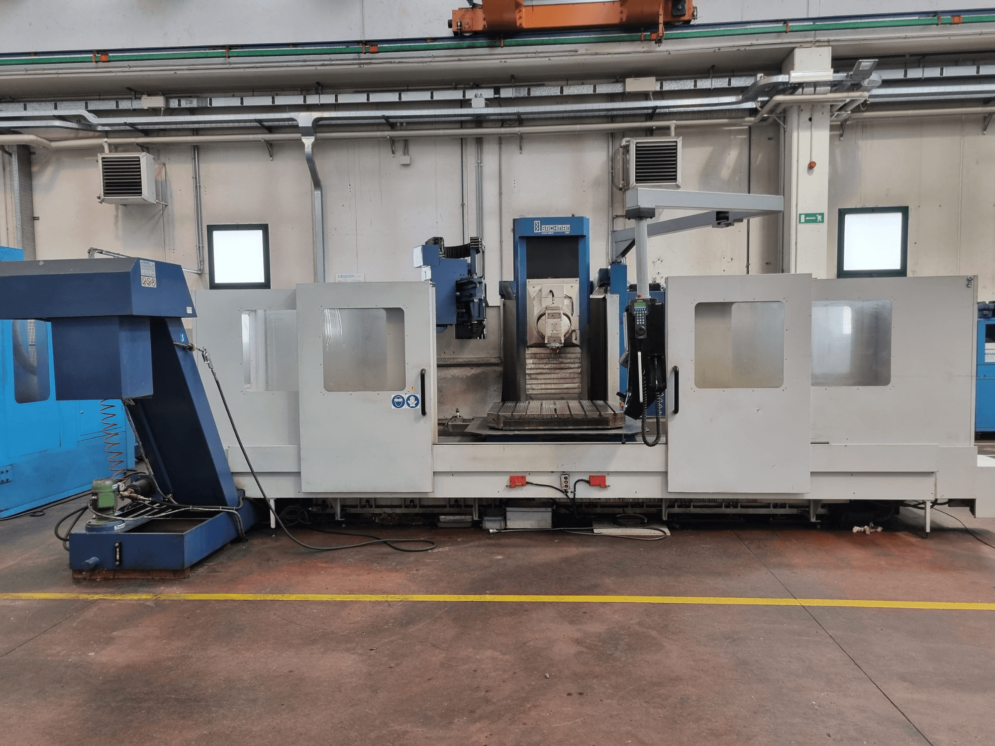 CNC freesmachine van "Brembana", zijaanzicht met bedieningspaneel en werkgebied met een werktafel binnenin.