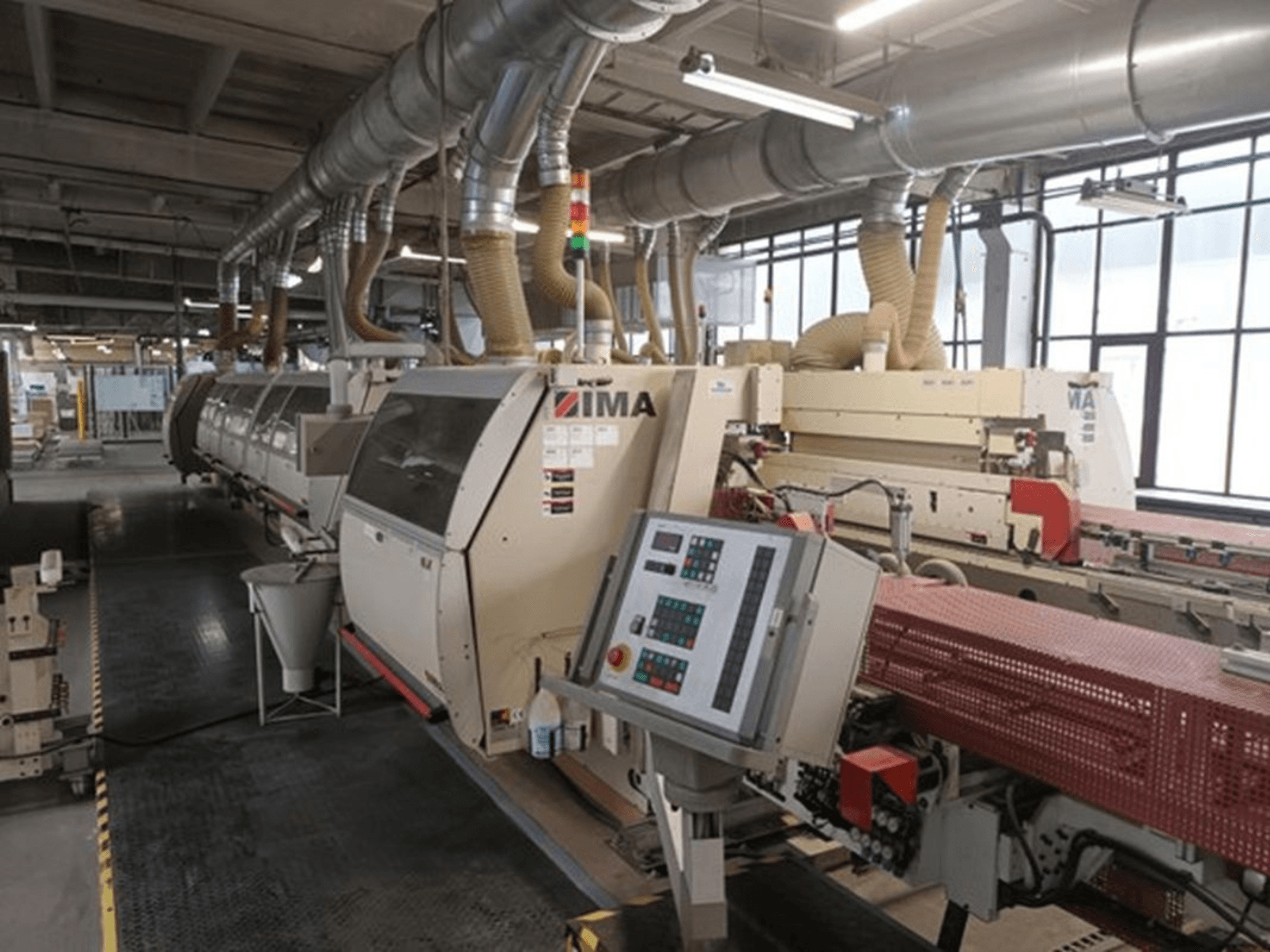 IMA industriële machines in een fabrieksomgeving, vooraanzicht, met bedieningspanelen en stofafzuigpijpen.