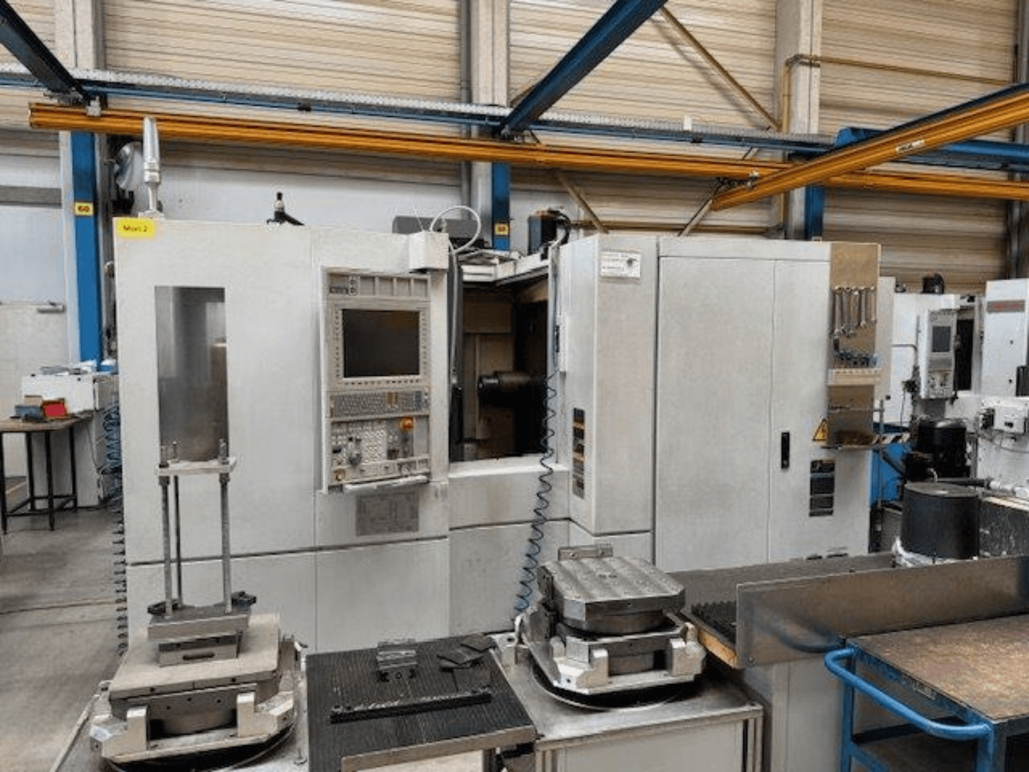 MORI SEIKI NH4000 DCG vooraanzicht van een horizontaal bewerkingscentrum met bedieningspaneel en werkstukken op de tafel.
