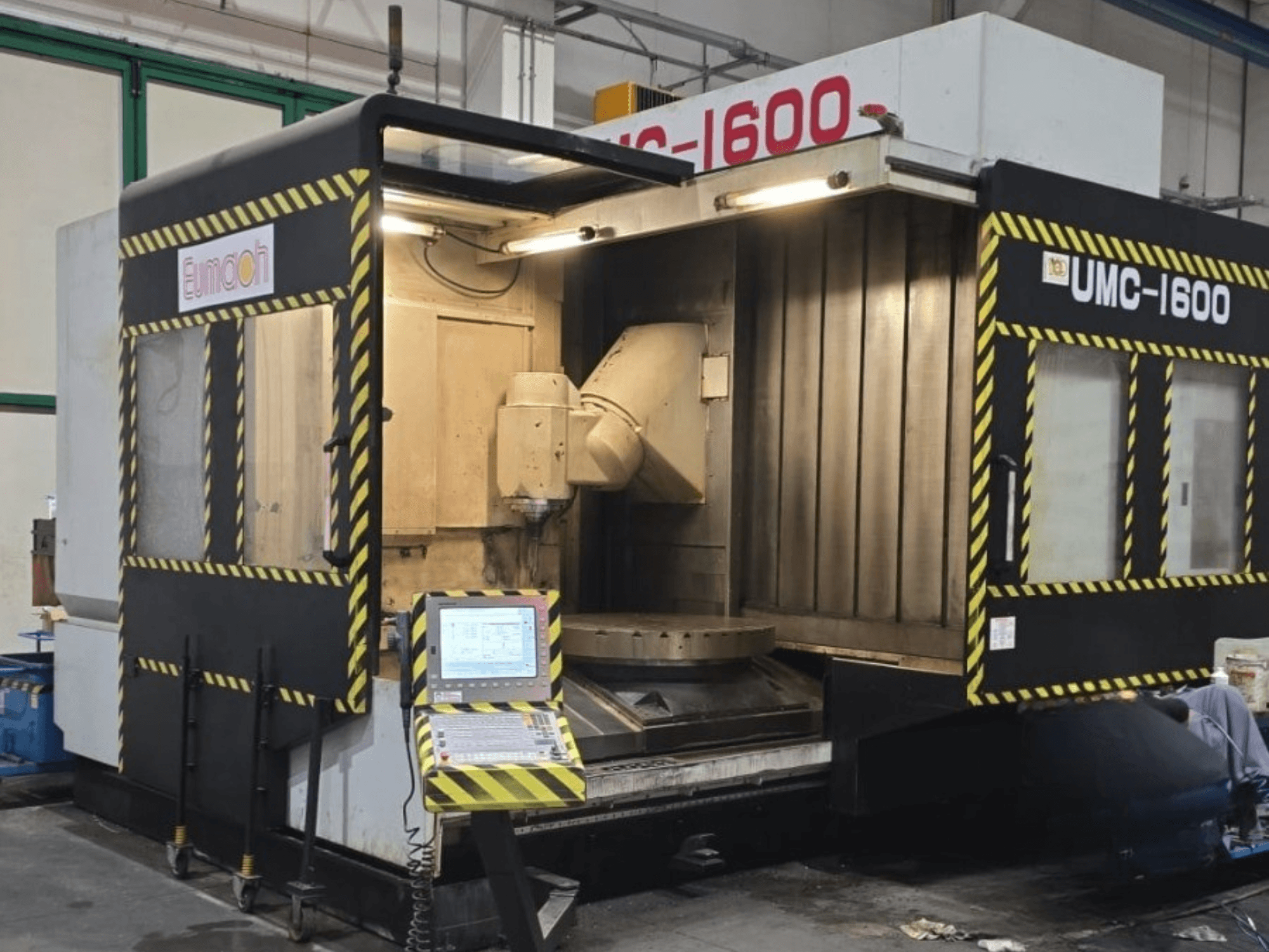 Eumach UMC-1600 verticaal bewerkingscentrum, vooraanzicht met bedieningselementen en bewerkingsgebied met veiligheidsstrepen.