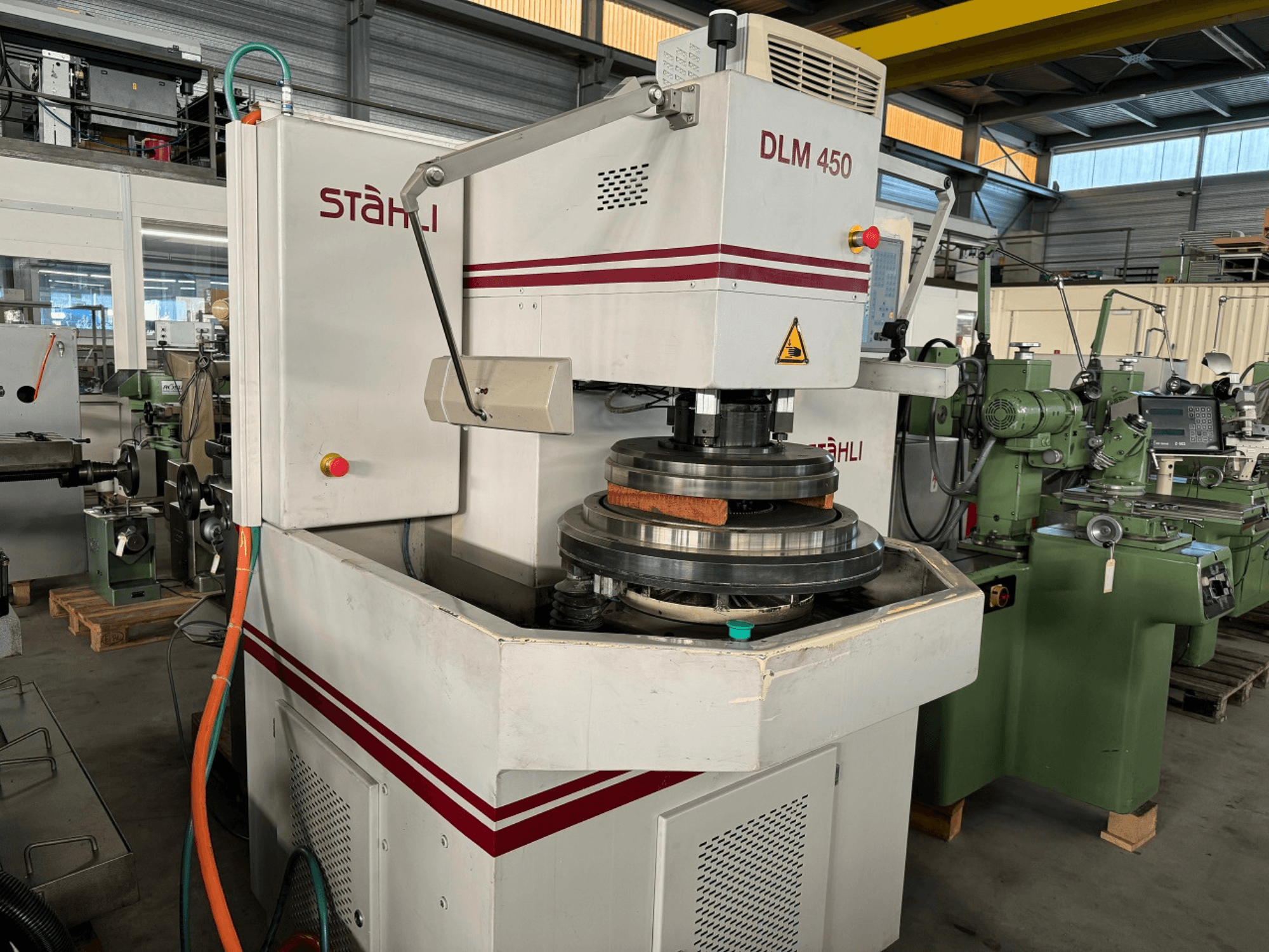 STAEHLI DLM 450 vlakslijpmachine, vooraanzicht met slijpschijf en bedieningspaneel, in een industriële omgeving.