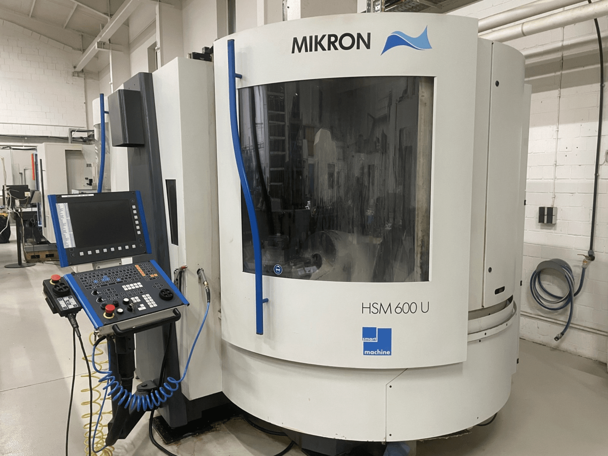 MIKRON HSM600U verticaal bewerkingscentrum getoond vanaf de voorkant, met een operationeel bedieningspaneel en groot kijkvenster.