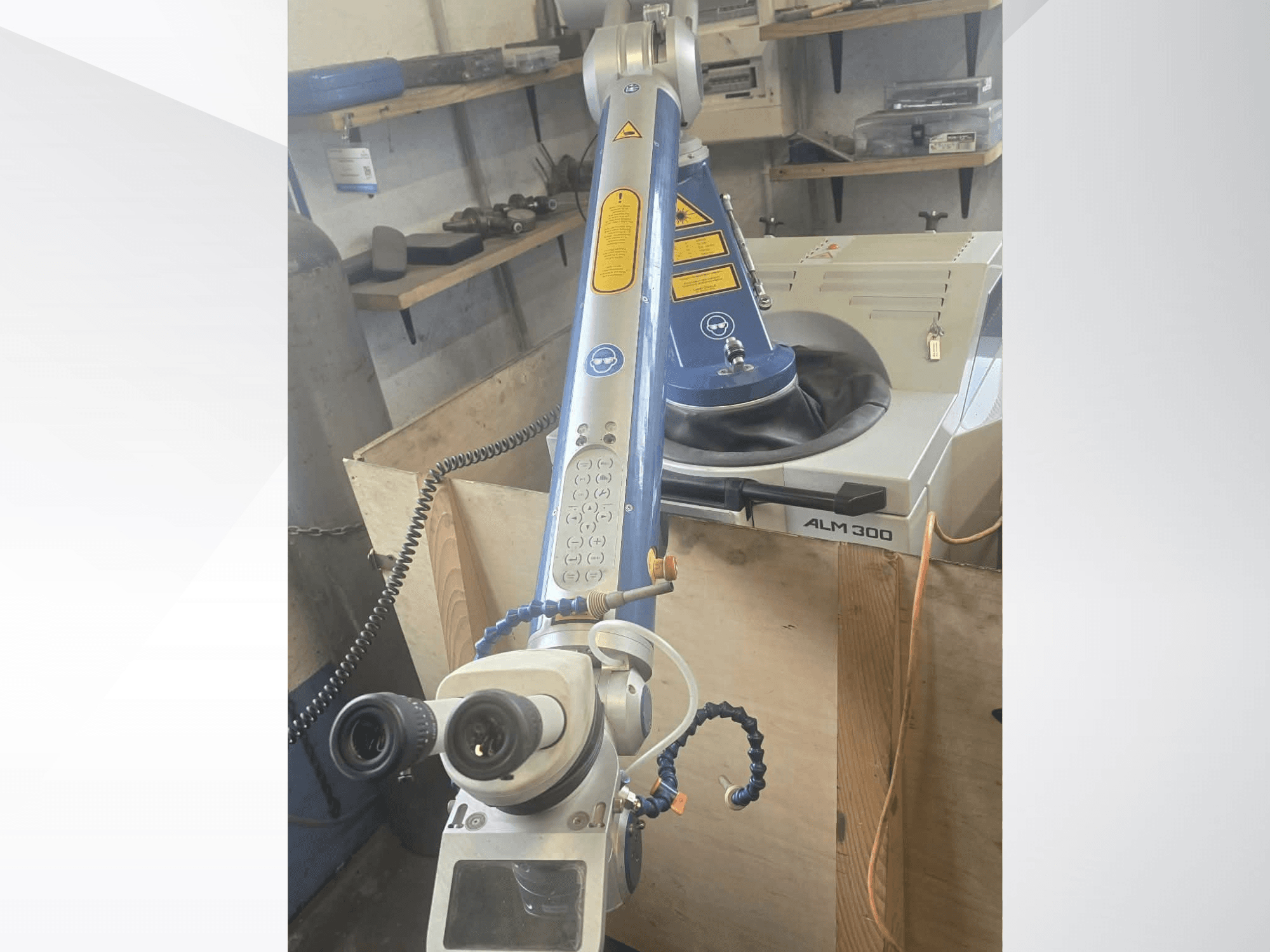 Vooraanzicht van de ALPHA LASER ALM 300-lasermachine, voorzien van een robotarm, optische lenzen en een bedieningspaneel.