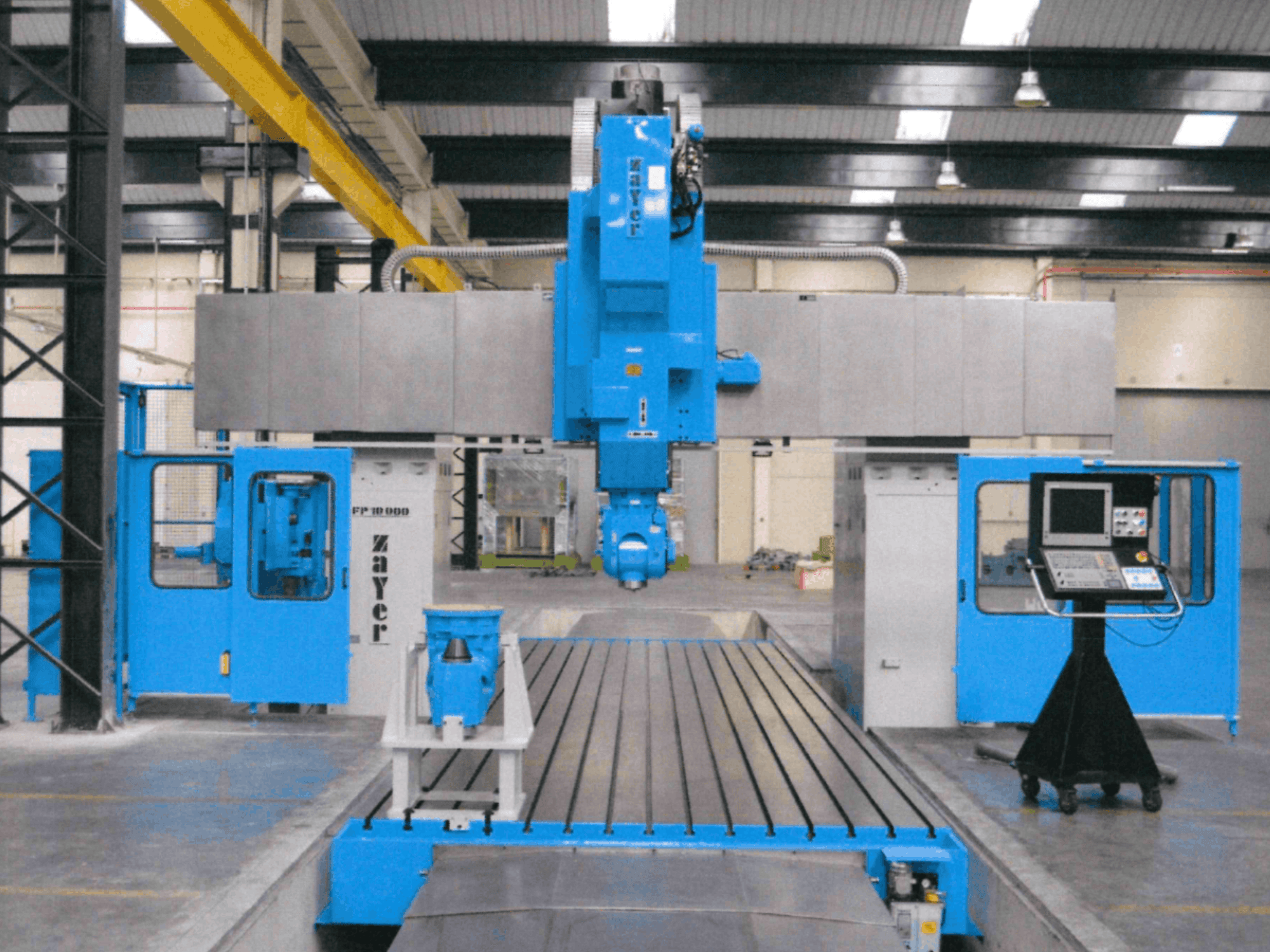 Vooraanzicht van de Zayer FP-10000 freesmachine met bed, waarbij de blauwe constructie, het bedieningspaneel en de precisieonderdelen goed te zien zijn.