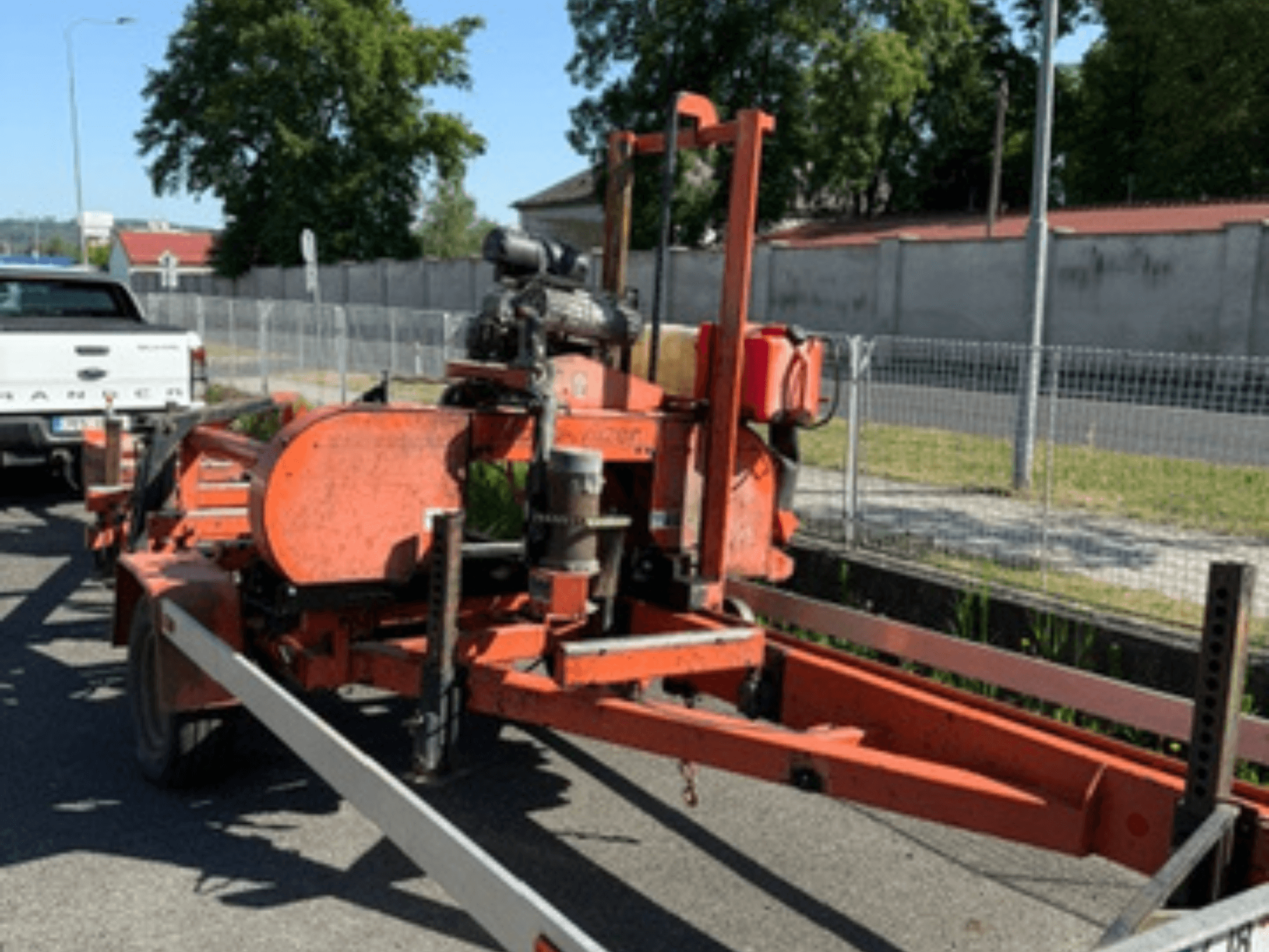 WOOD-MIZER LT40 houtbandzaag in oranje, zijaanzicht op een aanhangwagen met zichtbare wielen en motoronderdelen.