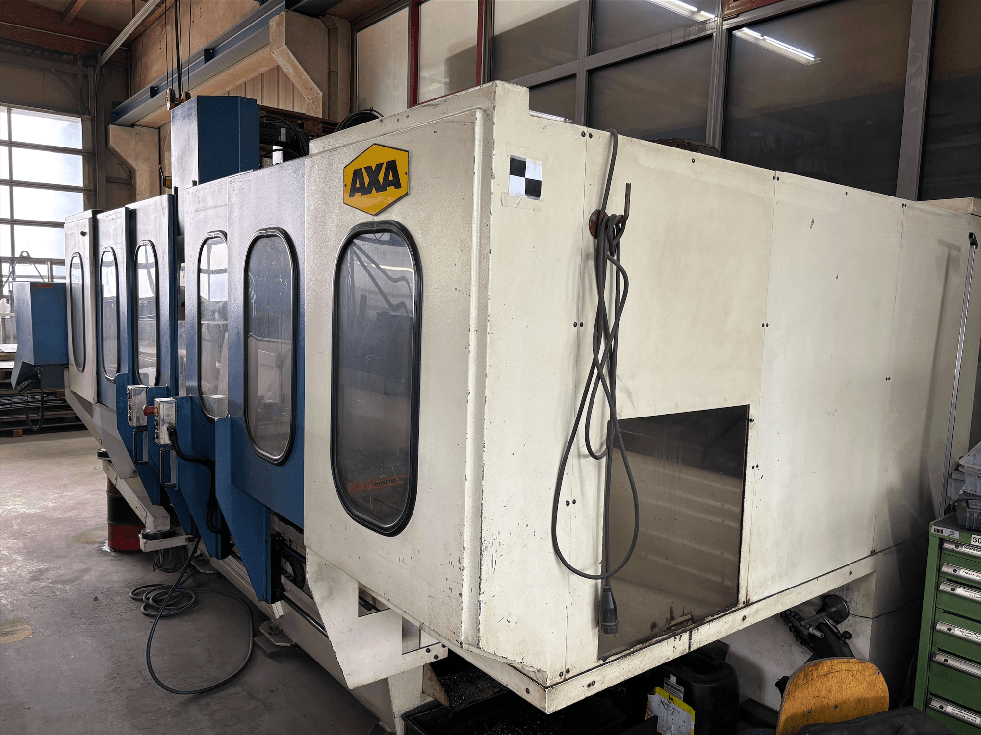 AXA VSC-1-M/C verticaal bewerkingscentrum, vooraanzicht, met een grote witte kast en blauw bedieningspaneel.