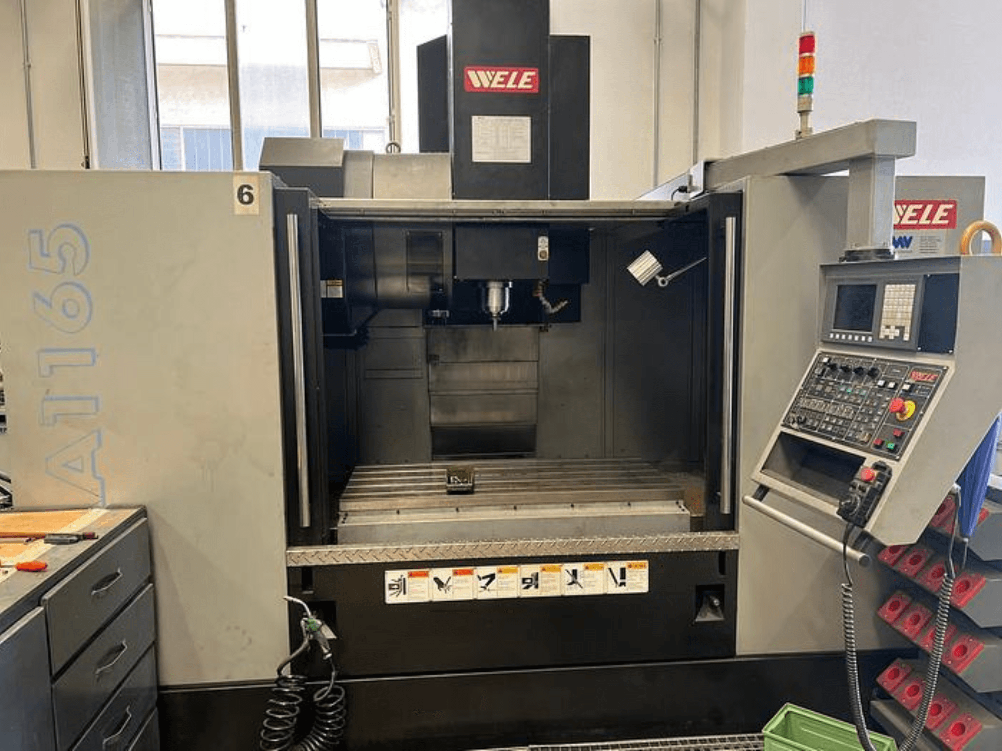 WELE A165 CNC bewerkingscentrum, vooraanzicht, met bedieningspaneel, gereedschaphouder en werktafel zichtbaar. Industriële omgeving.