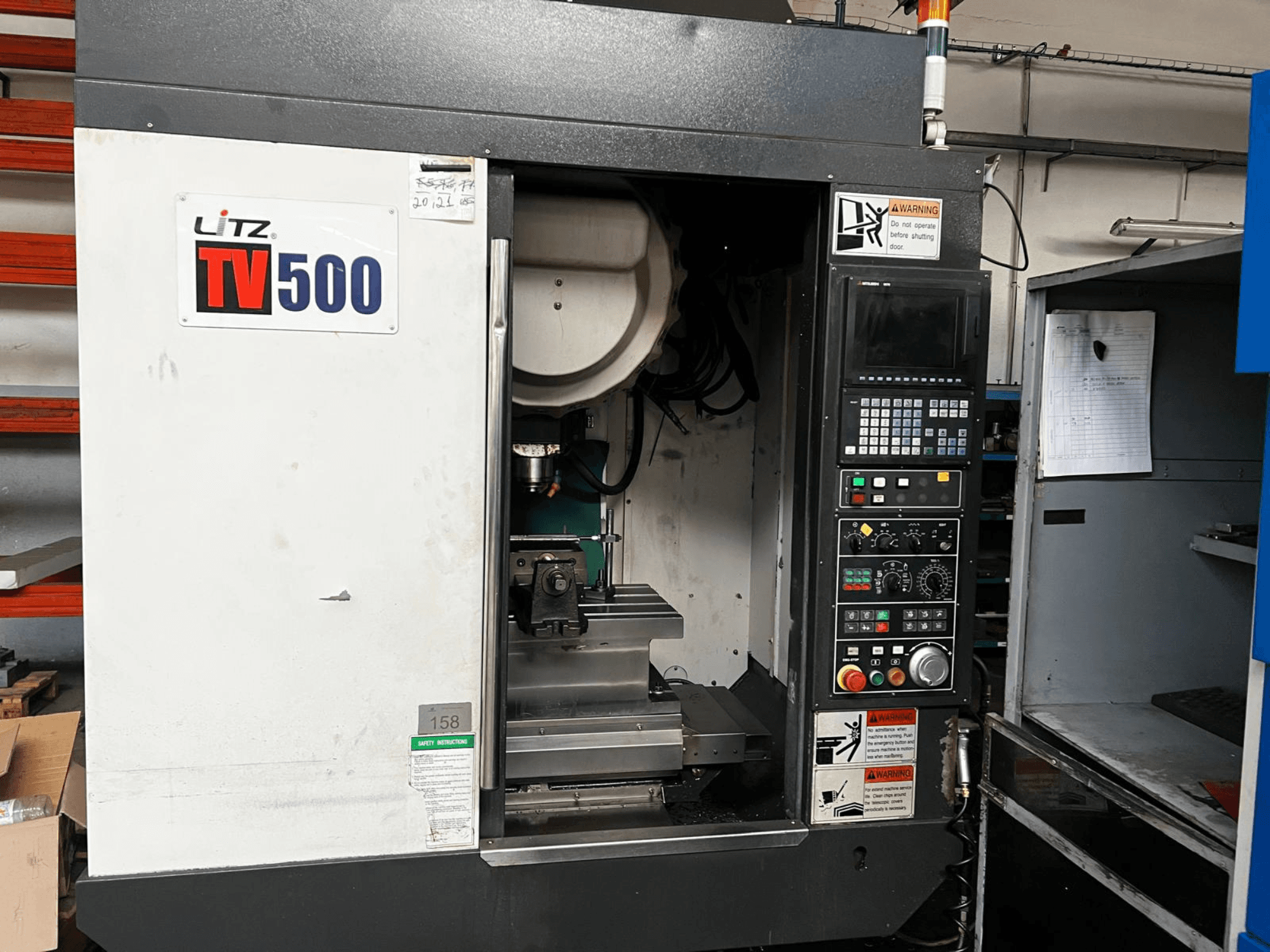 Vooraanzicht van het verticale bewerkingscentrum Litz TV500, met het bedieningspaneel, de spil en het werkgebied binnenin de machine.