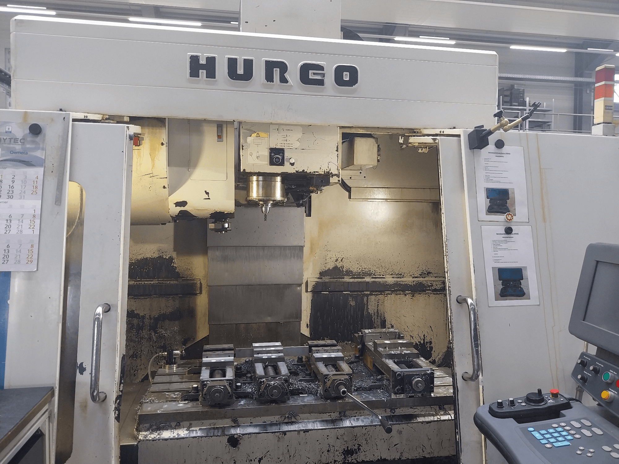 Hurco VMX 42 verticaal bewerkingscentrum vooraanzicht, toont werktafel met opspanmiddelen en bedieningspaneel, licht versleten staat.