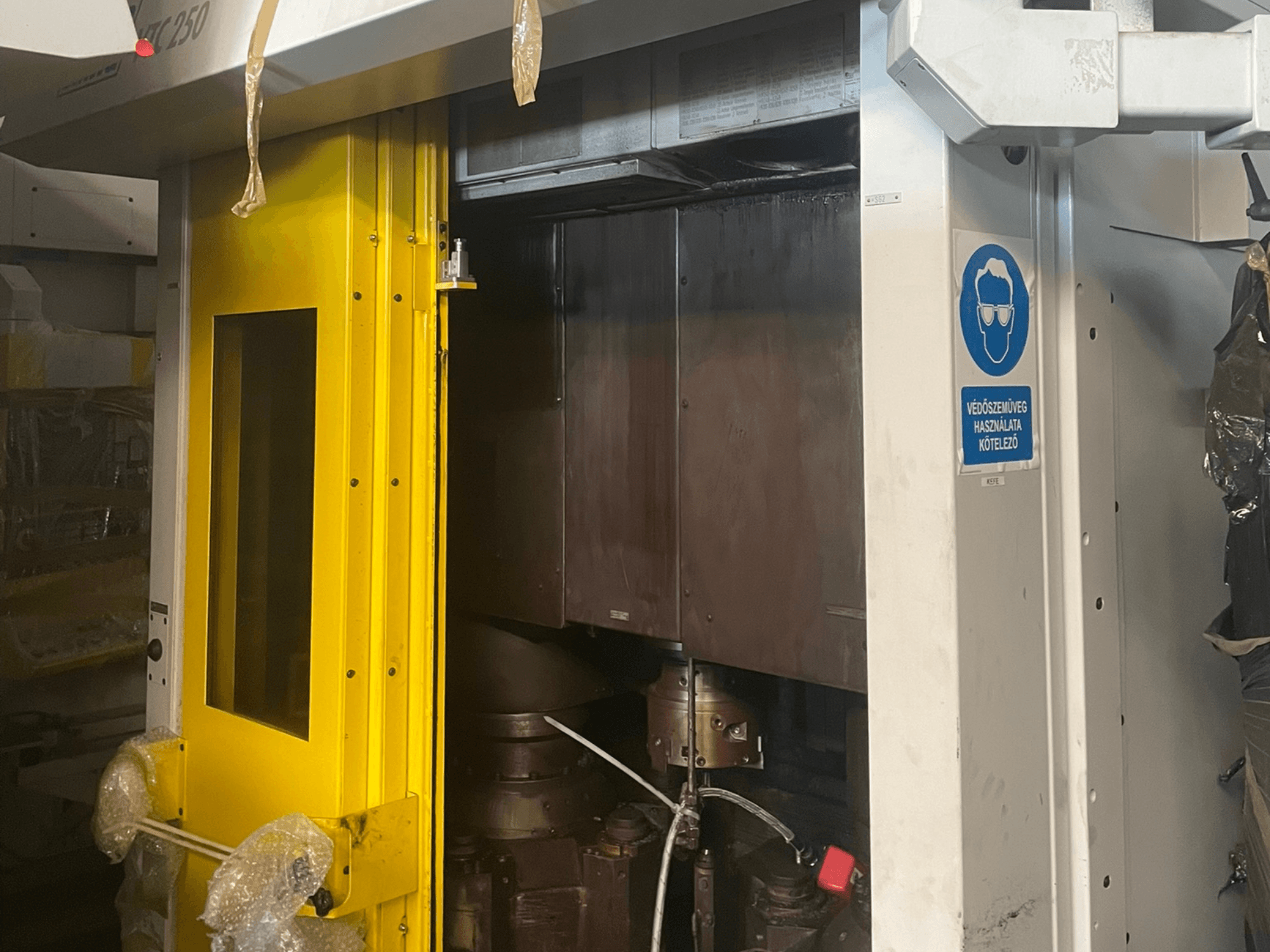 Gele toegangsdeur van een machine met veiligheidsteken, vooraanzicht van een industriële machine model Z250, met de interne onderdelen.