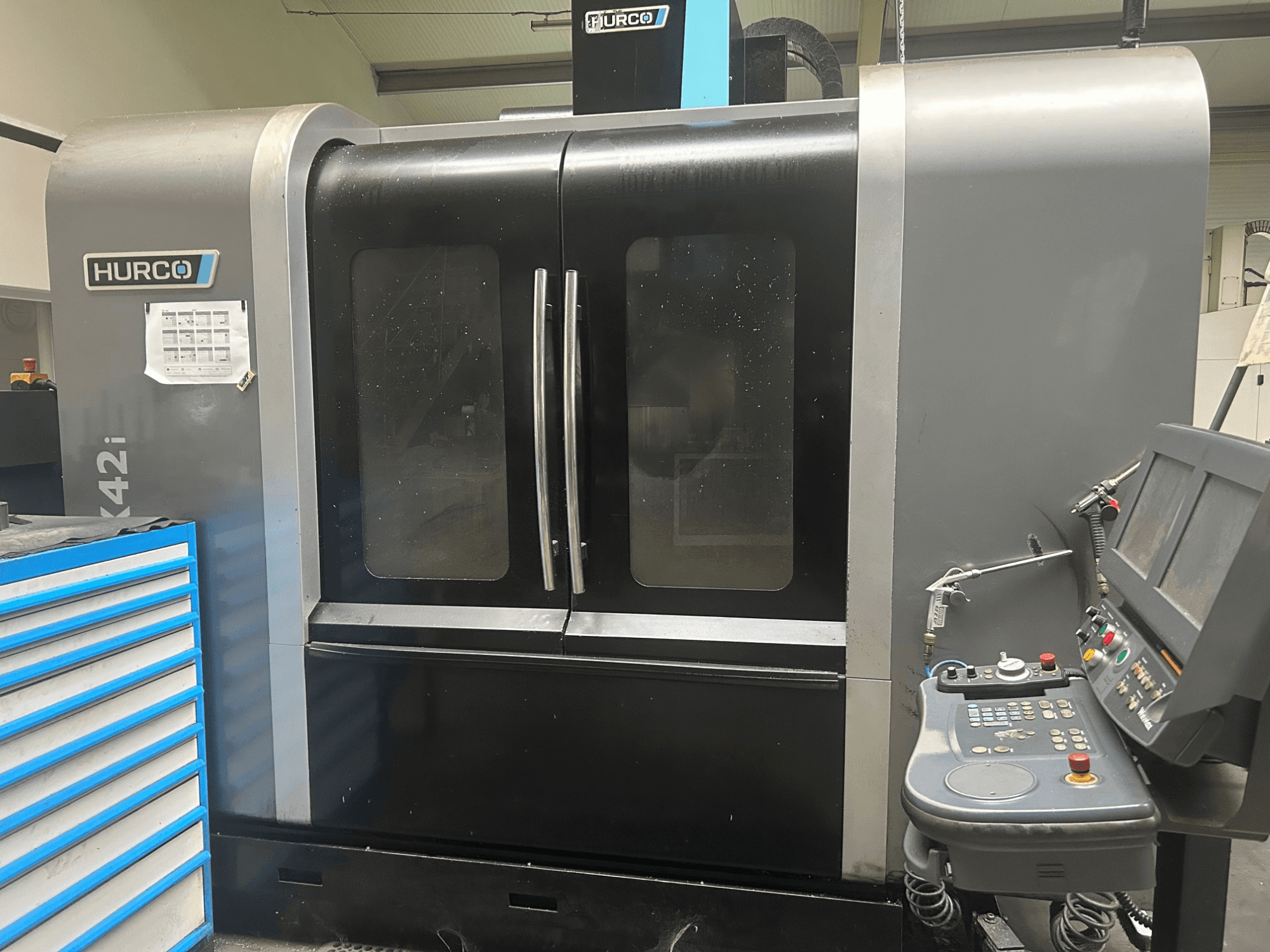 Hurco VMX42i CNC machine, vooraanzicht met bedieningspaneel aan de zijkant, met dubbele deuren en zichtbare technische details.
