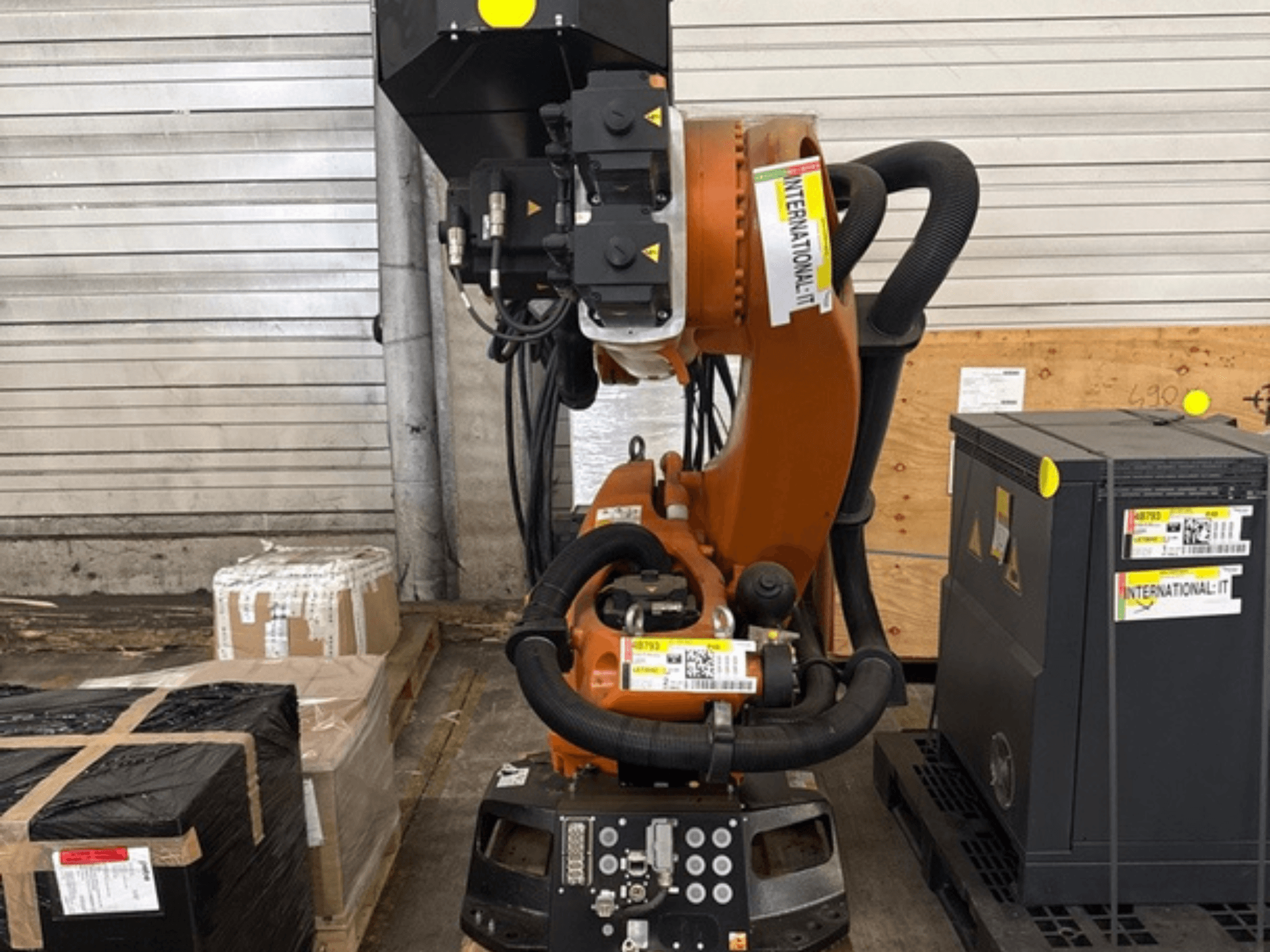 KUKA KR 210 R2700 extra robotarm in vooraanzicht, tentoongesteld op een pallet naast verpakkingen en apparatuur.
