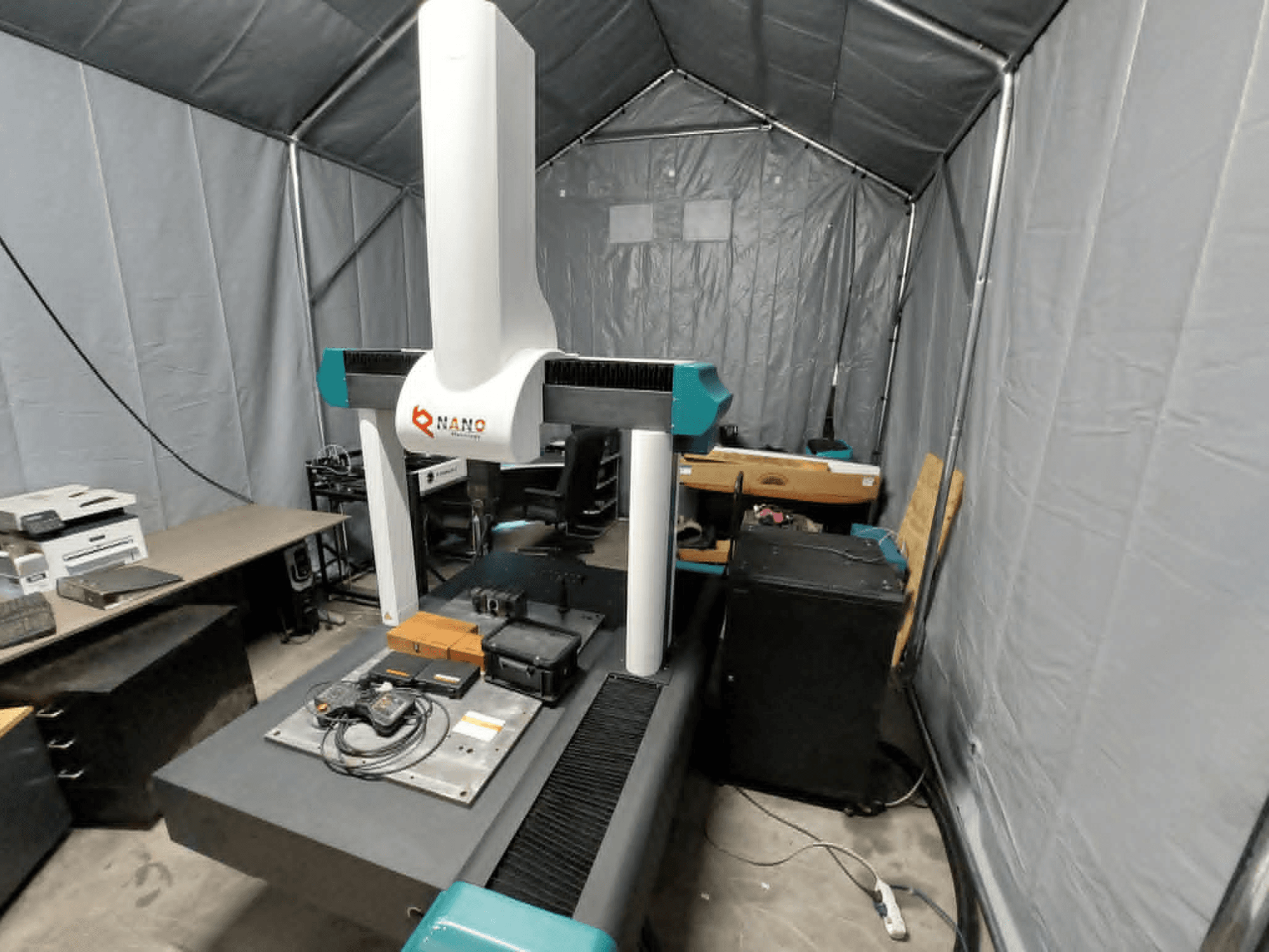 NANO METROLOGY Micr 7106 CMM in een tent; vooraanzicht toont de arm van de machine en het meetplatform met accessoires.