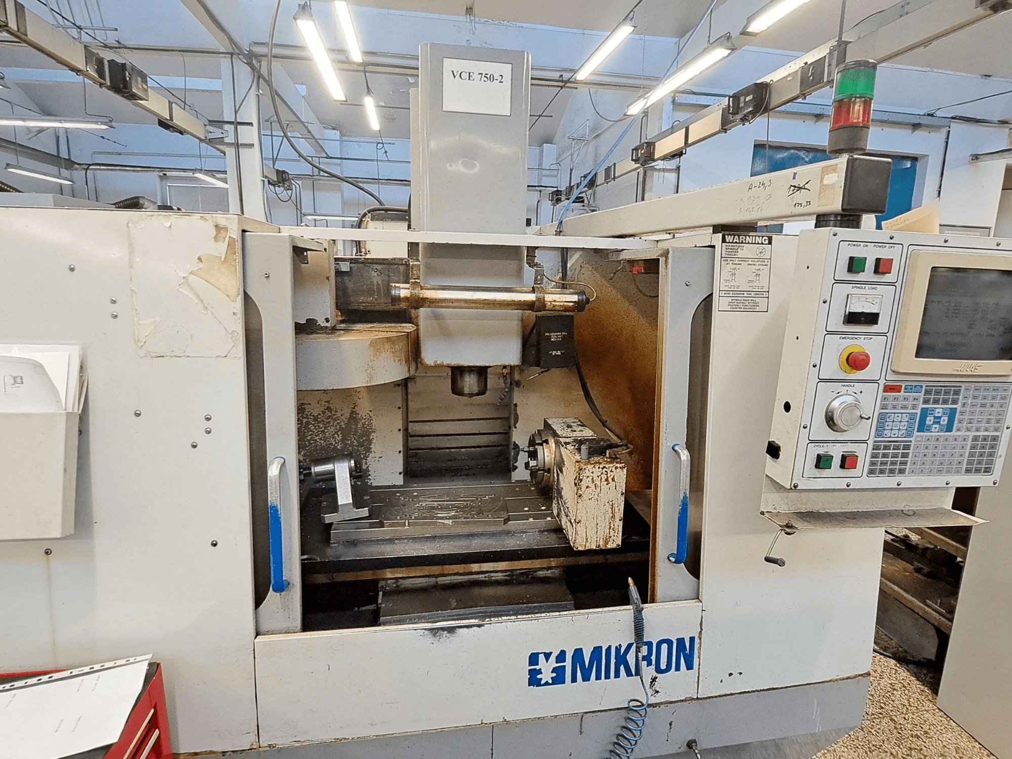 Mikron VCE 750-2 CNC freesmachine, vooraanzicht, met bedieningspaneel en spindel in bewerkingsgebied, vertoont slijtage en vuil.