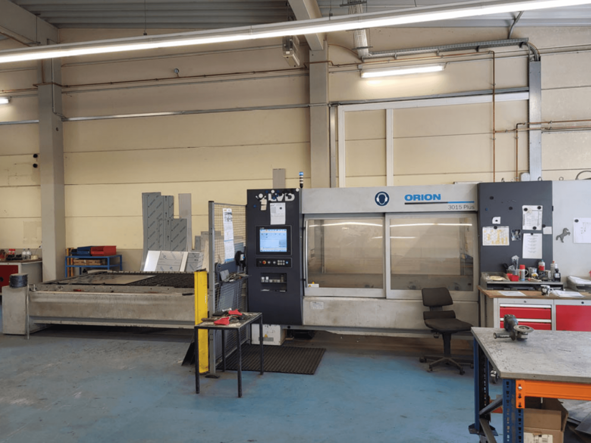 ORION 3015 Plus snijmachine in een werkplaats, vooraanzicht, met bedieningspaneel en omliggende werktafels.