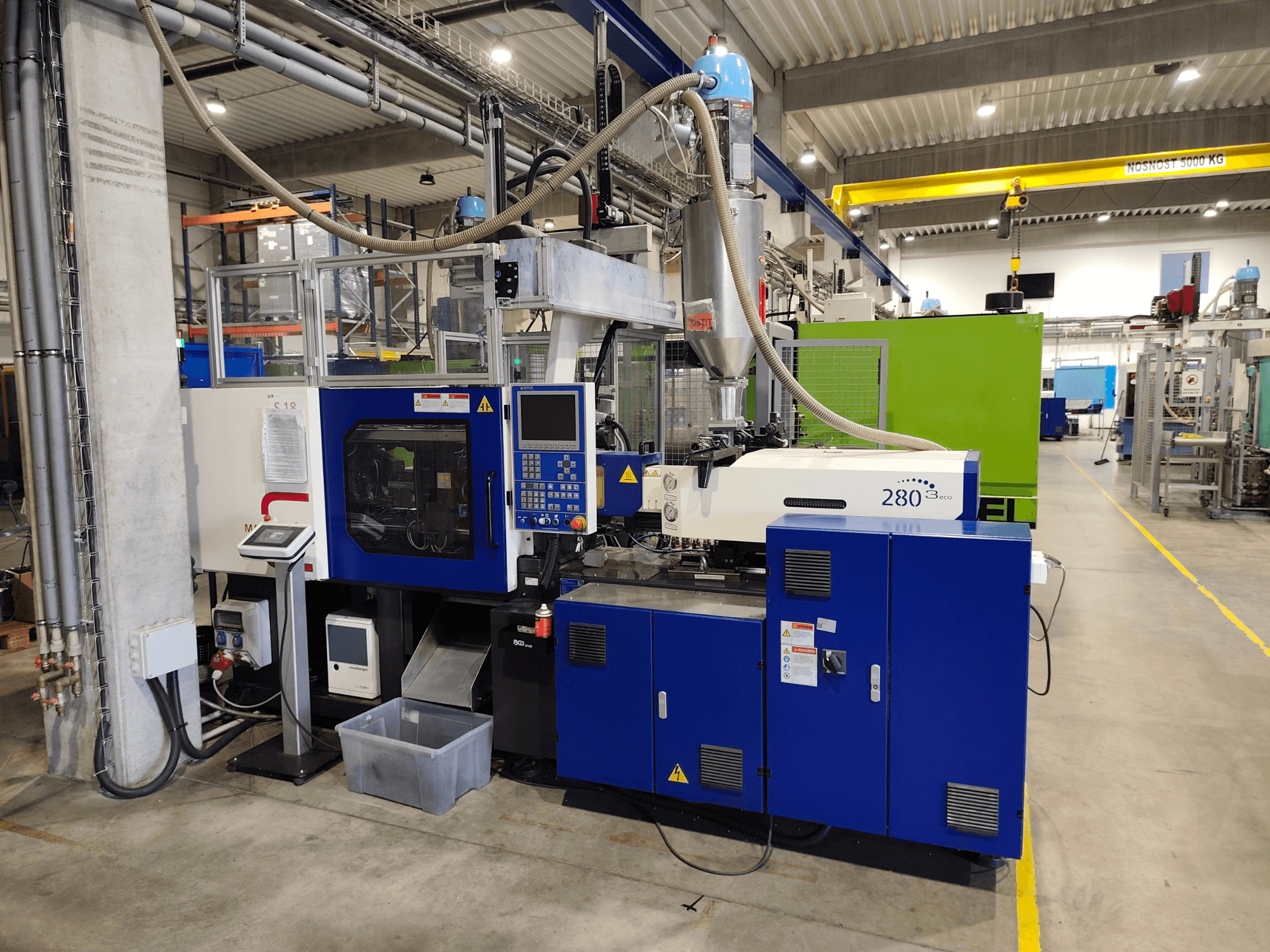 Hydraulische spuitgietmachine HAITIAN Mars III MA 900/280 A ECO, zijaanzicht, met bedieningselementen en toevoereenheid.