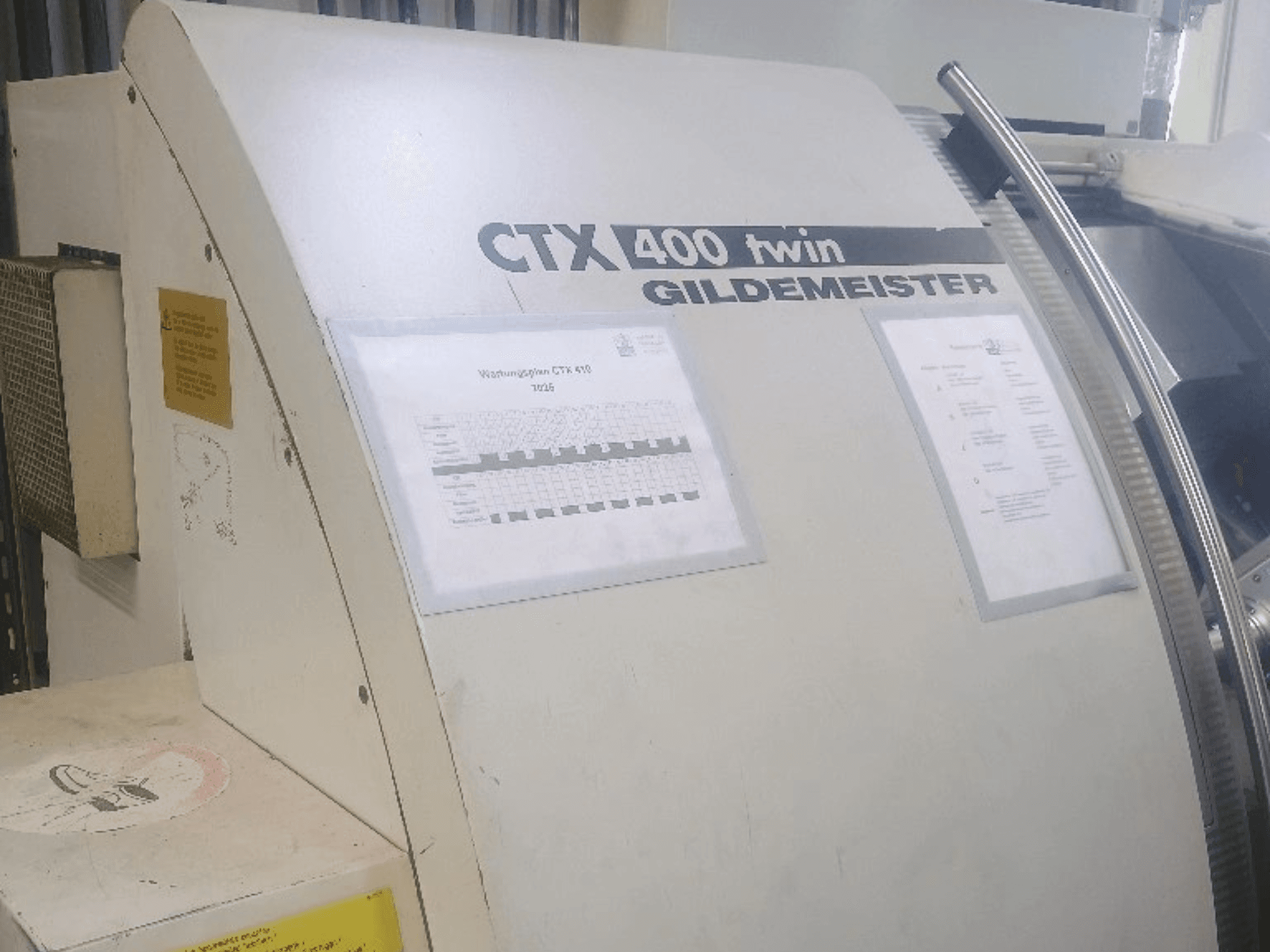 Gildemeister CTX 400 dubbele horizontale draaimachine, vooraanzicht, met bedieningspanelen en technische documentatie.