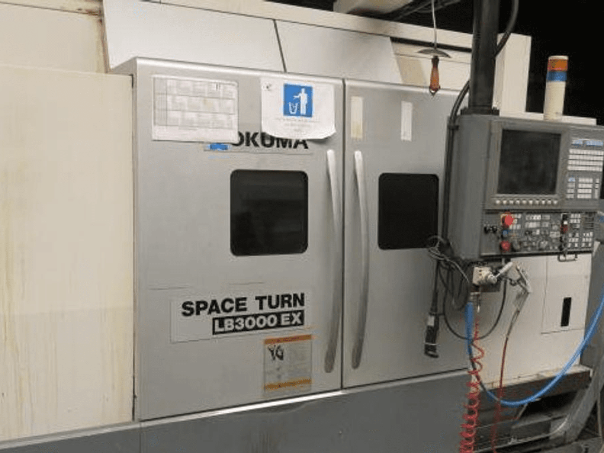 Okuma Space Turn LB3000 EX CNC draaibank, zijaanzicht, met bedieningspaneel, twee deuren en zichtbare bedrading.