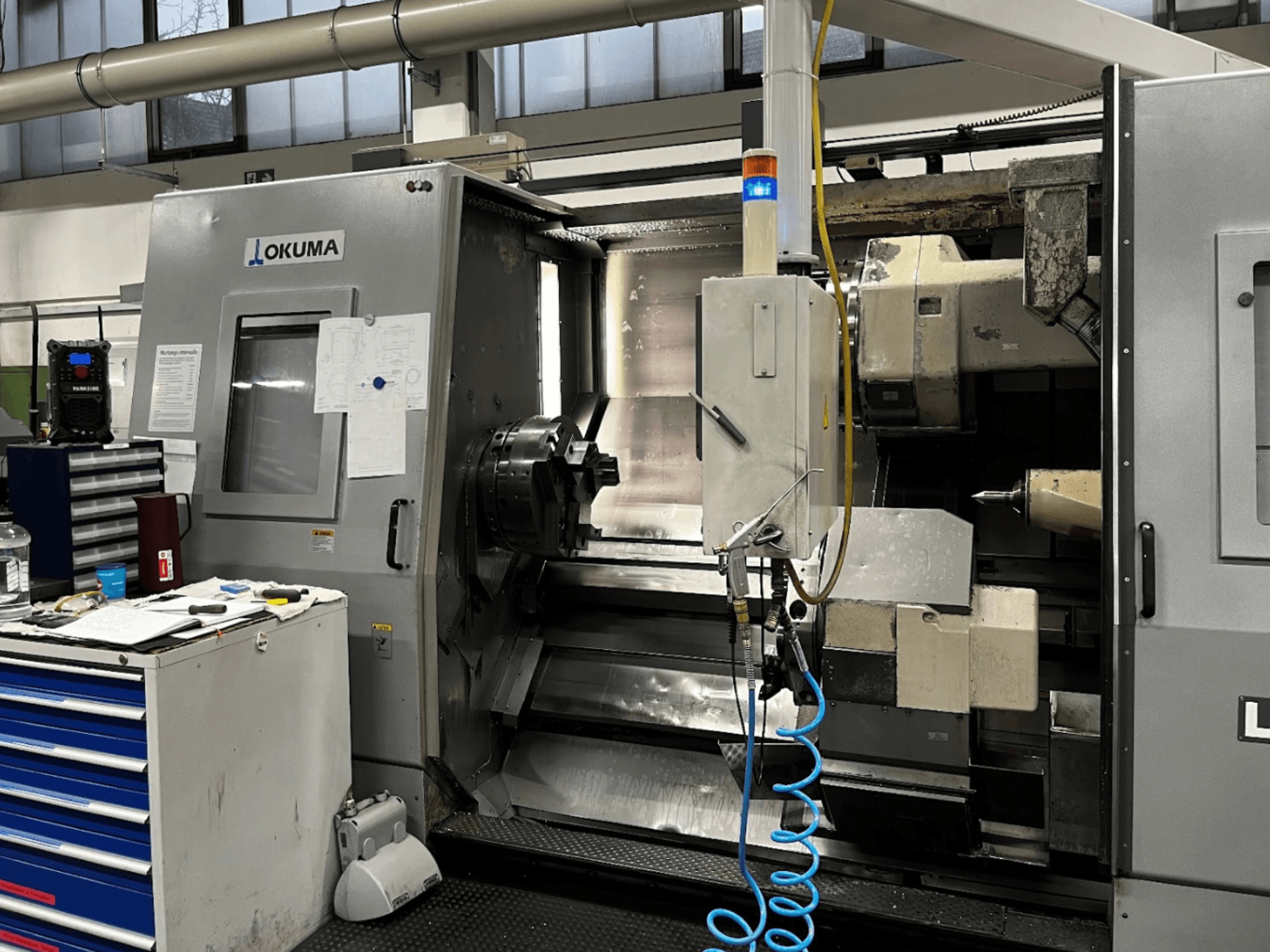 Okuma LU35-M horizontale draaimachine, vooraanzicht. Voorzien van bedieningspaneel, gereedschappen en grote klauwplaat voor verspanende bewerkingen.