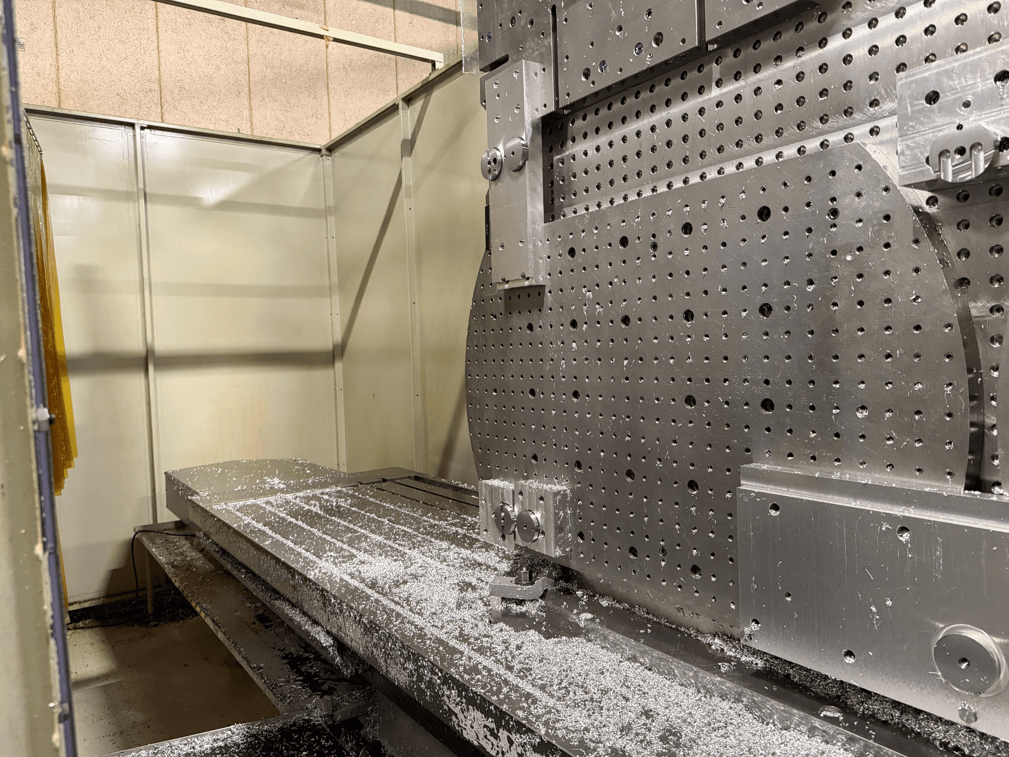 Close-up vooraanzicht van het KIHEUNG KNC-U1000 universeel bewerkingscentrum, met een metalen werktafel met aluminium spanen.