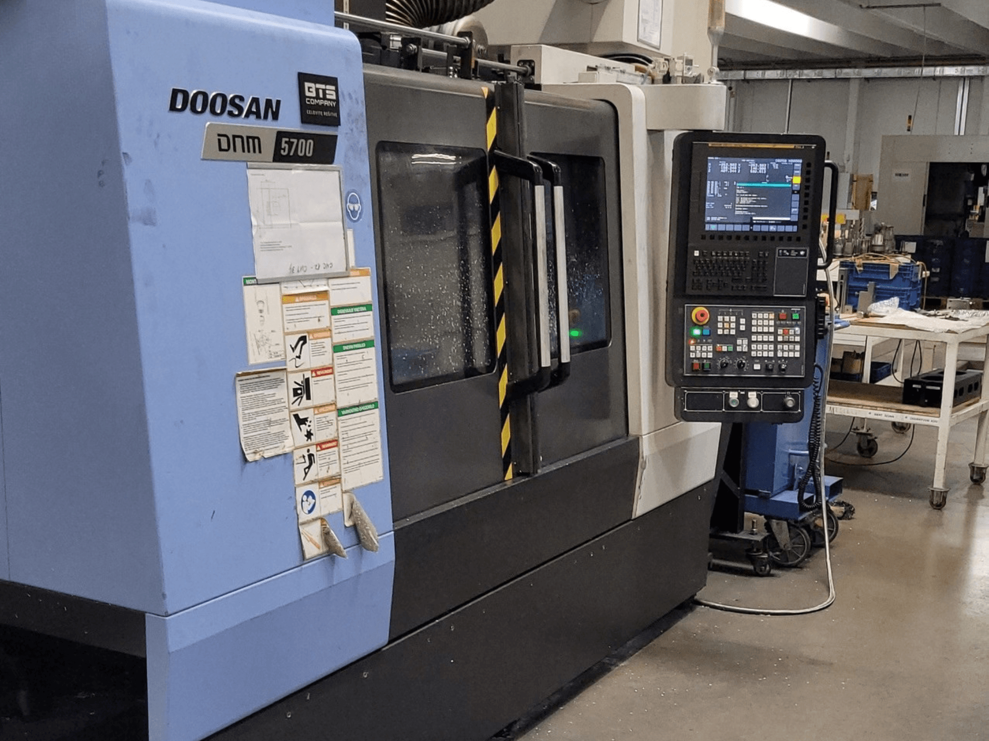 DOOSAN DNM 5700 verticaal bewerkingscentrum, vooraanzicht, met het bedieningspaneel en de bedieningselementen.